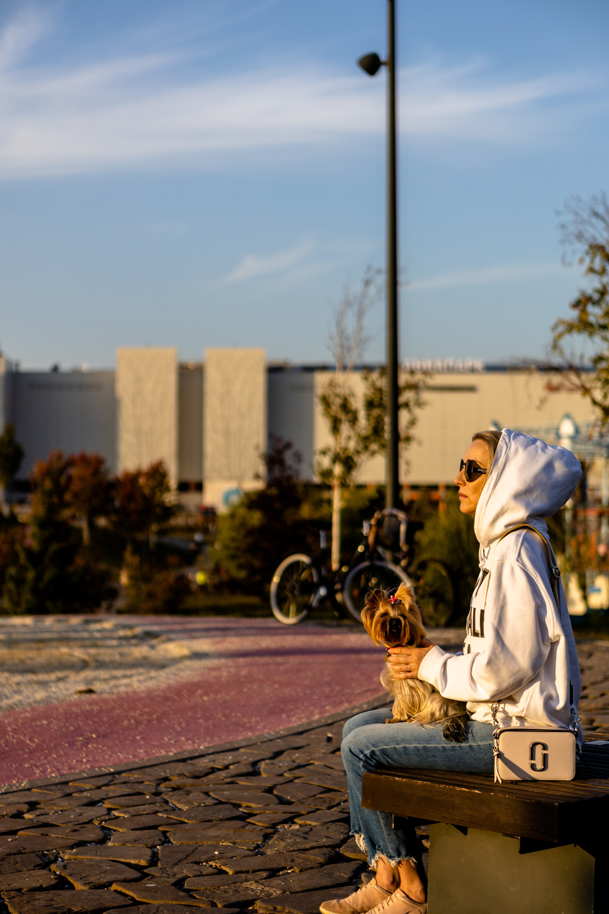 Девушка сидит на скамейке и держит на руках собачку