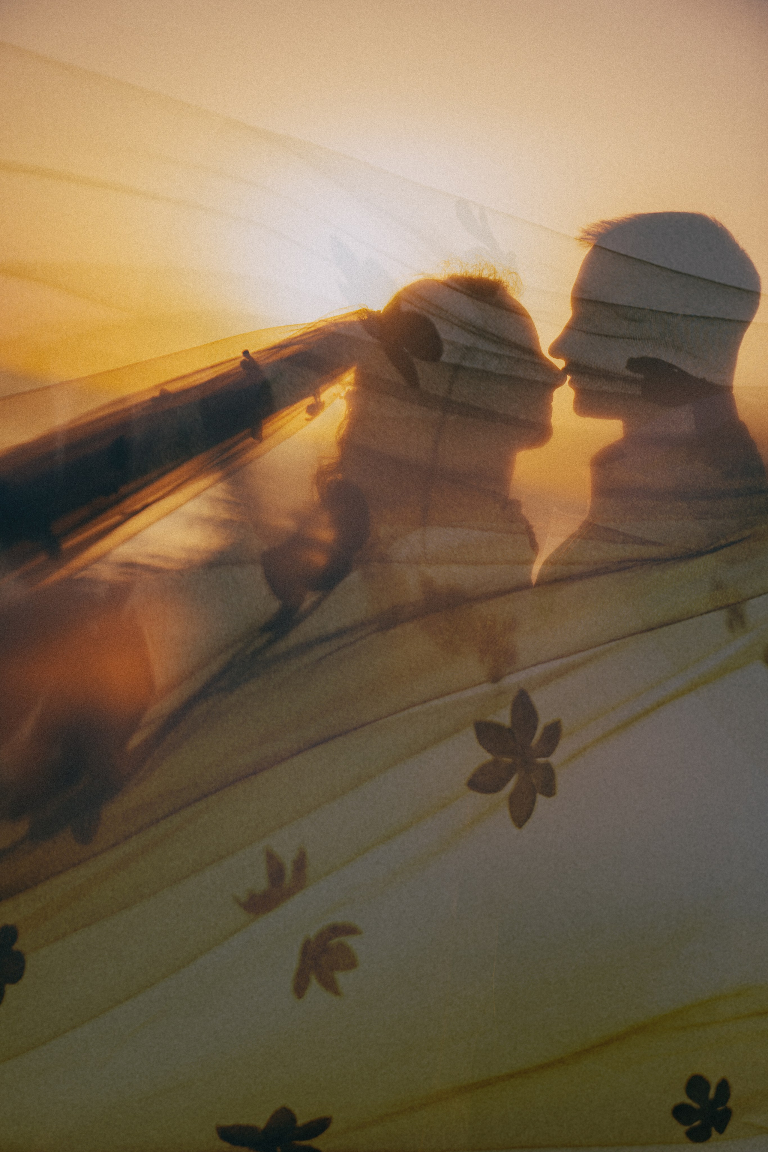 Счастливая пара жених и невеста целуется на фоне волн  скал и заката у океана.