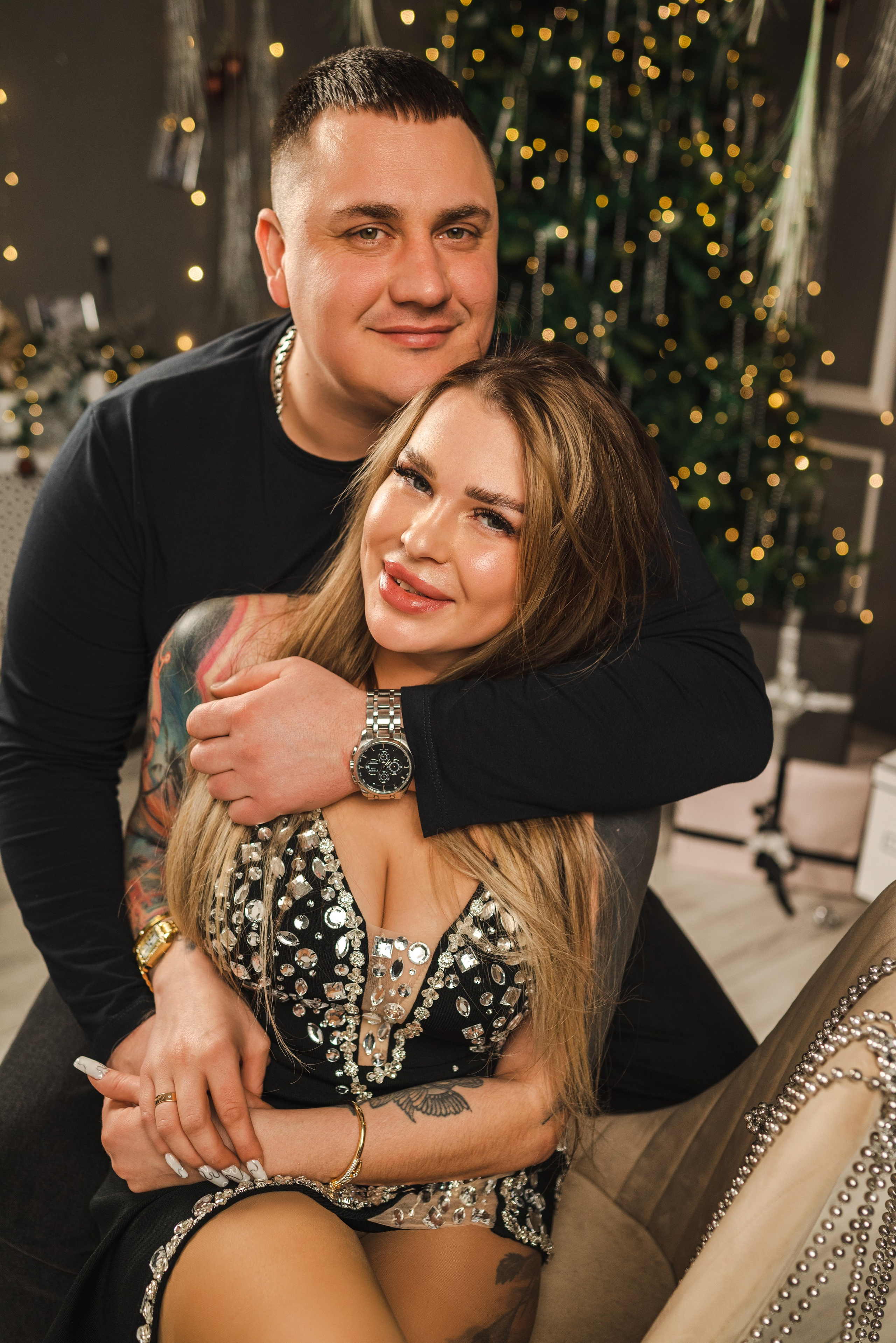 Крутая новогодняя фотосессия 2025 в фотостудии в Каменске-Шахтинском и Ростове-на-Дону. Двое пара молодых сидят на фоне новогодней елки. Фотограф Ольга Сагал 