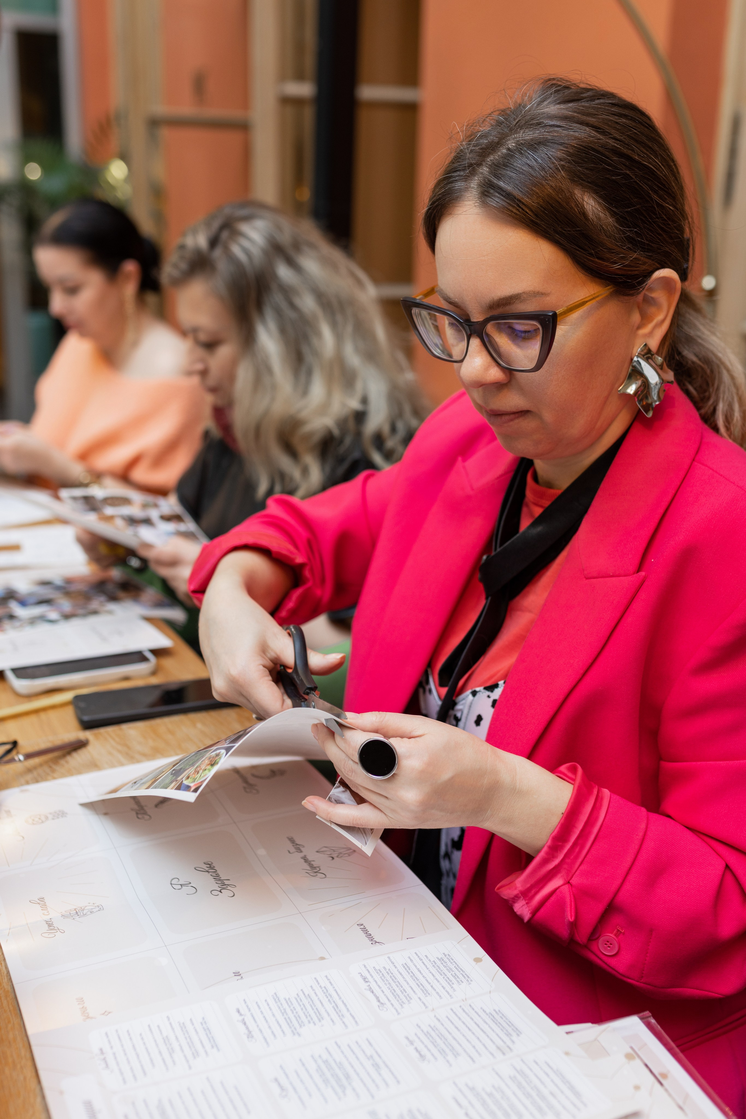 Девушка сидит за столом,  у нее в руках ножницы