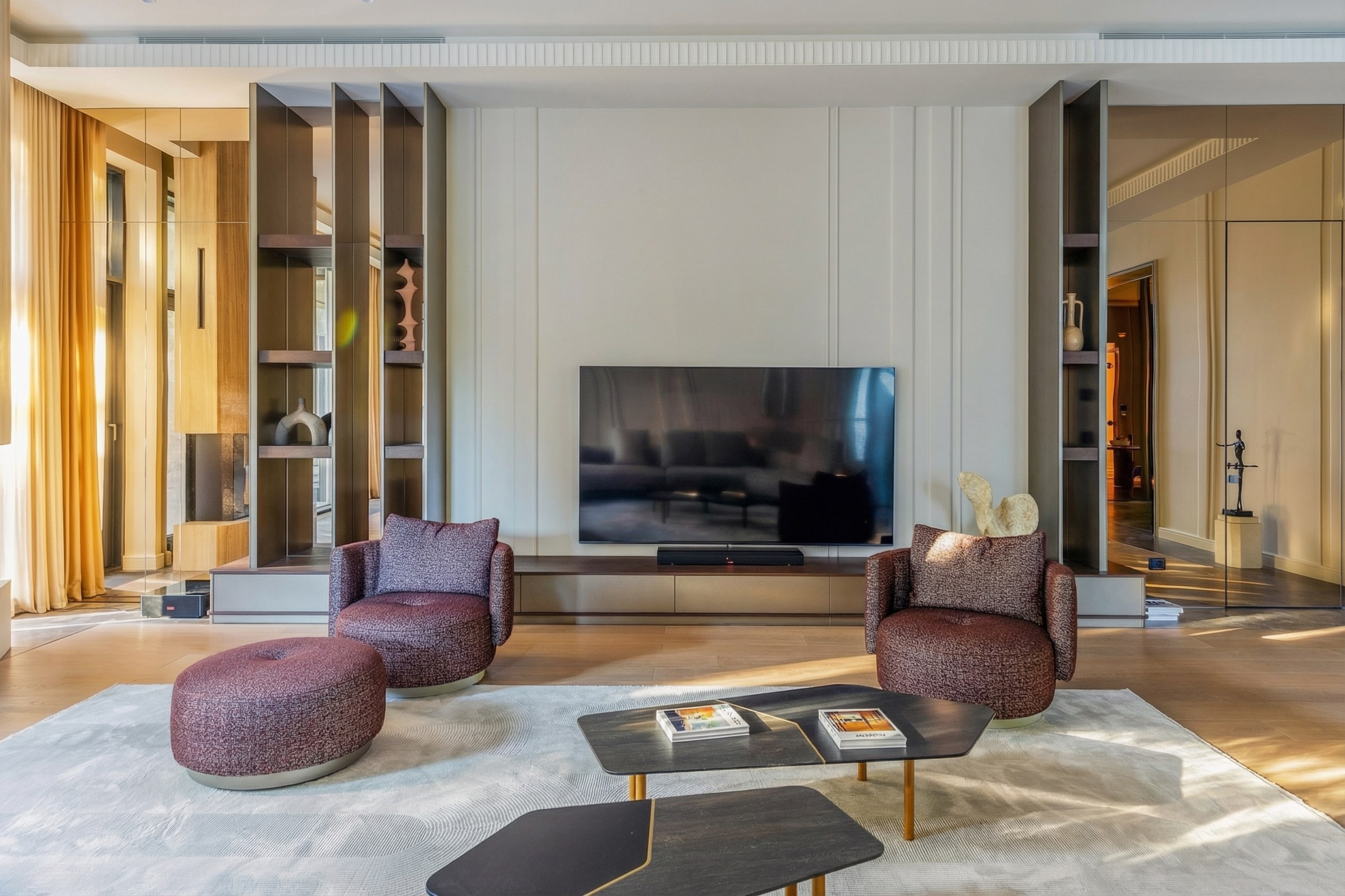 Центральная ТВ-зона гостиной с симметричными стеллажами, зеркальными панно и дизайнерской мягкой мебелью винного оттенка, проект Валерии Котович, дом 1240 м² в Подмосковье.