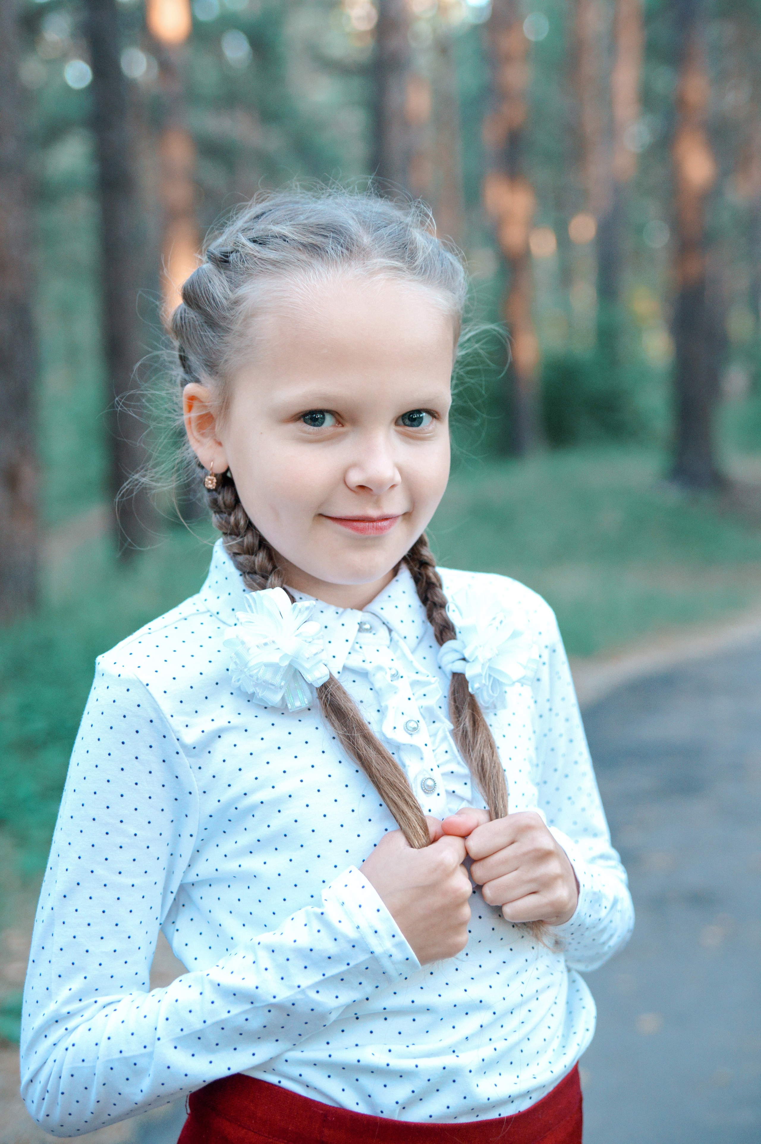 Детская фотосессия осенью - школьница стоя с косичками крупный портрет