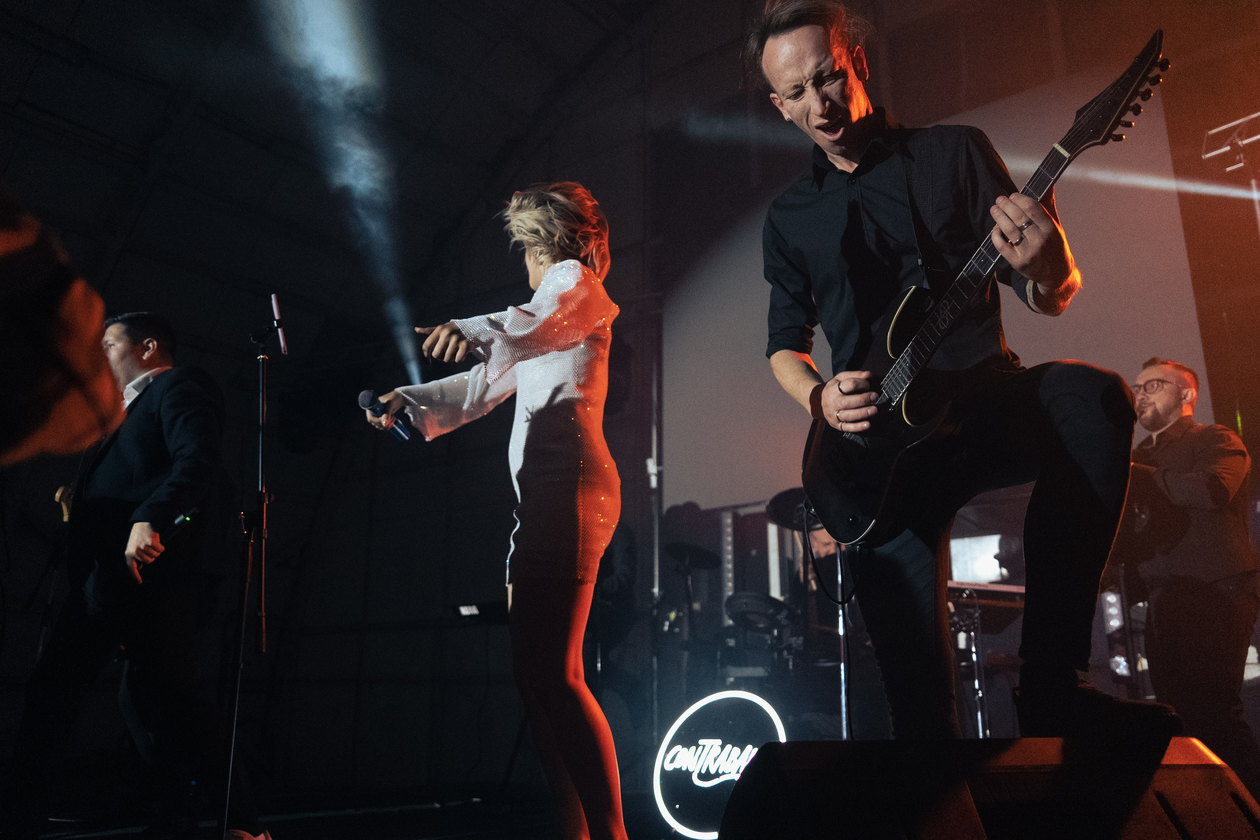 Группа людей поет и танцует на сцене, мужчина с микрофоном в центре, корпоративное мероприятие