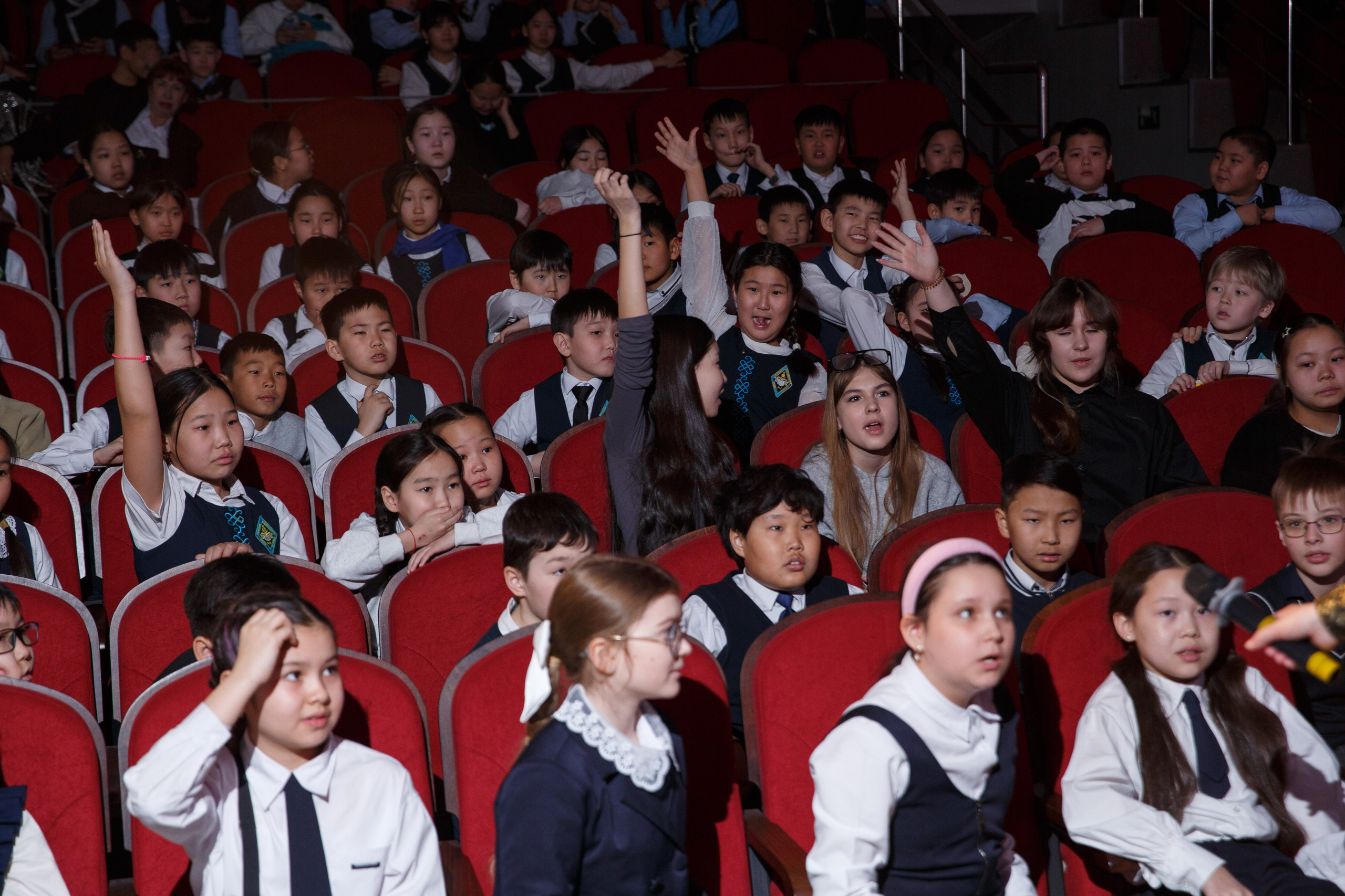 Дети активно участвуют в мероприятии, поднимая руки.