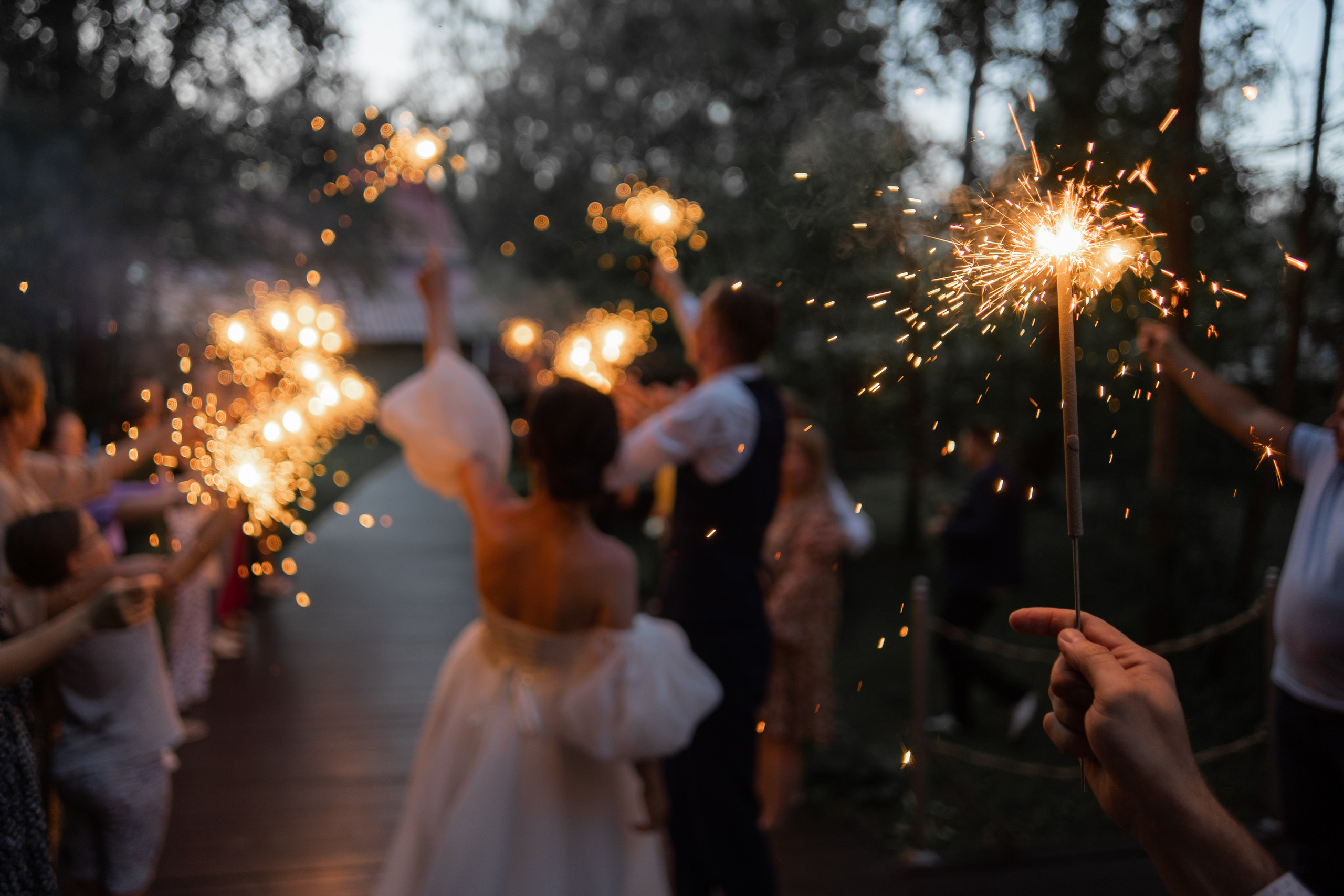 жених и невеста идут через гостей с бенгальскими огнями