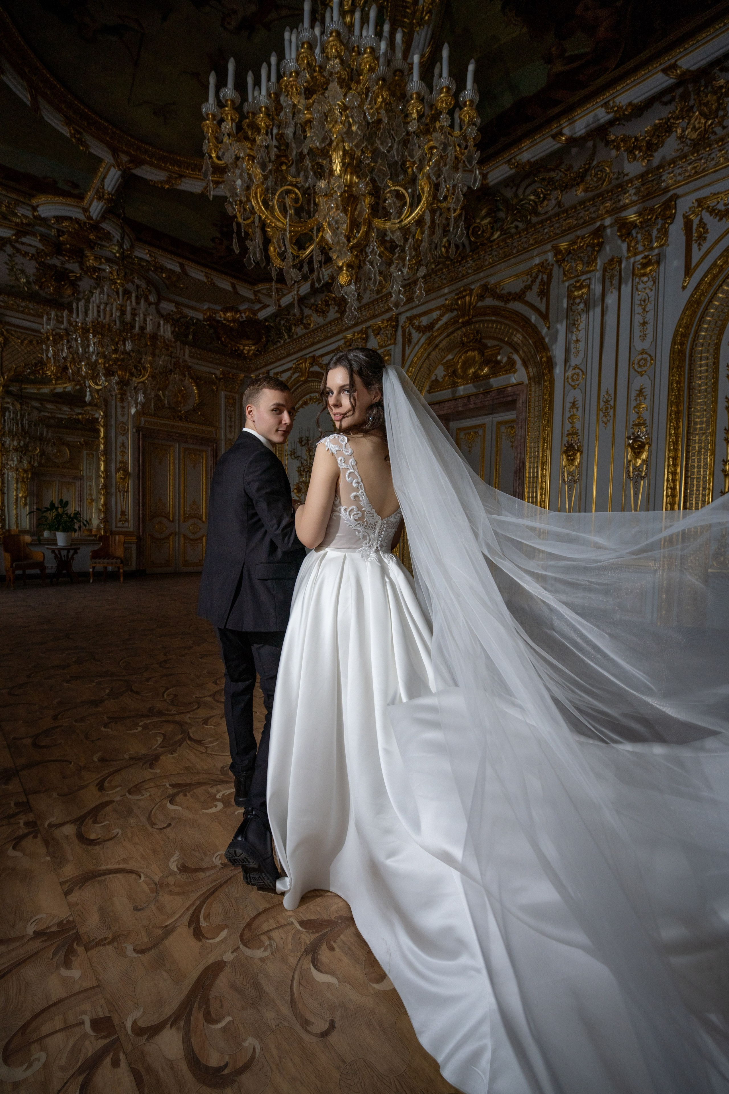 Свадебная фотосессия в Санкт-Петербурге в Особняке Половцева или Дом Архитектора. Жених красиво ведет в танце невесту, фата летит в золотом зале с красивыми люстрами