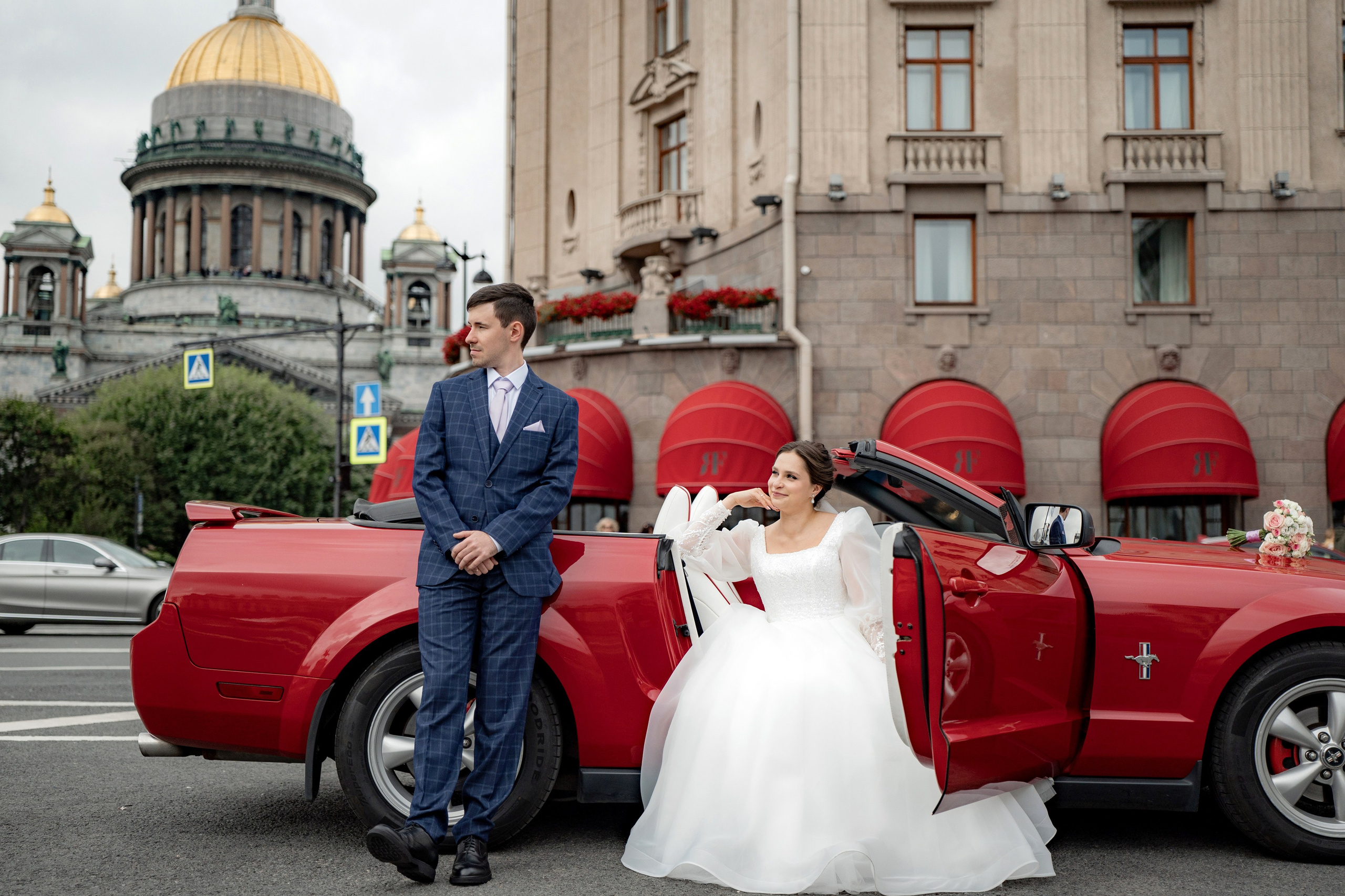 Свадебная фотосессия рядом с Исаакиевским собором и красным кабриолетом. Жених и невеста стоят у автомобиля на фоне Собора. Самые популярные места для свадебной фотосессии в Санкт-Петербурге