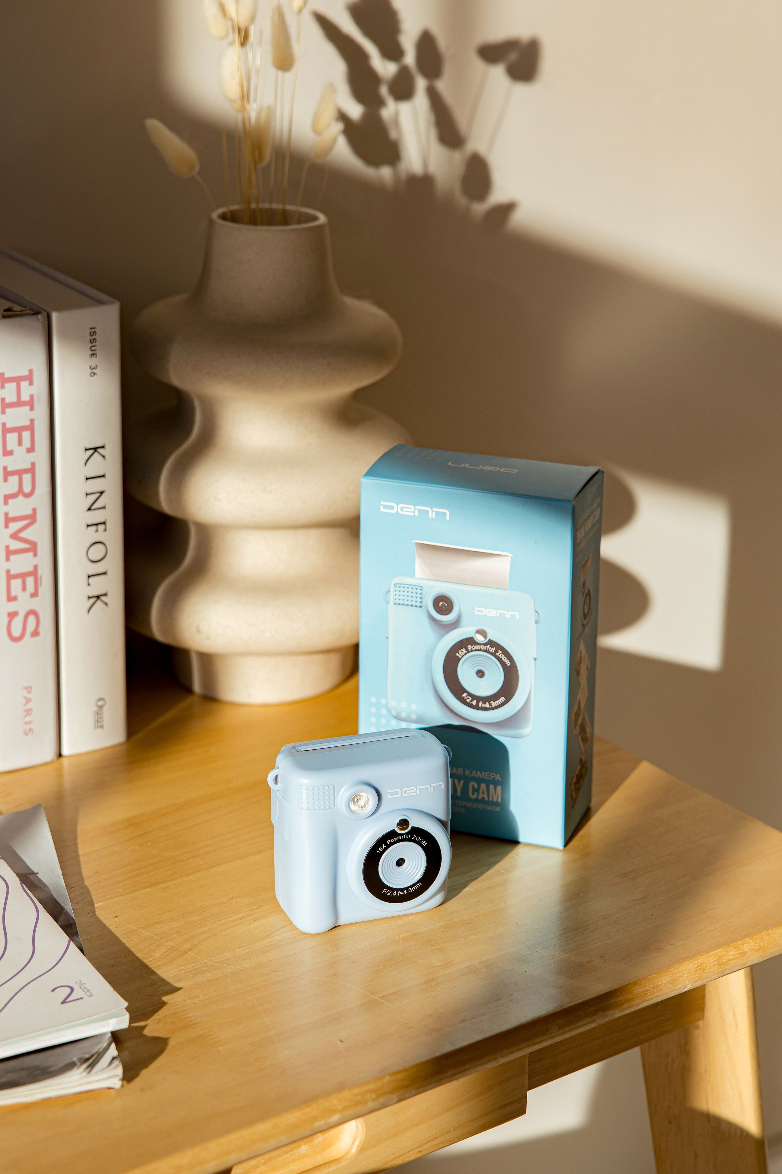 Коробка с фотоаппаратом моментальной печати стоит на столе на солнце