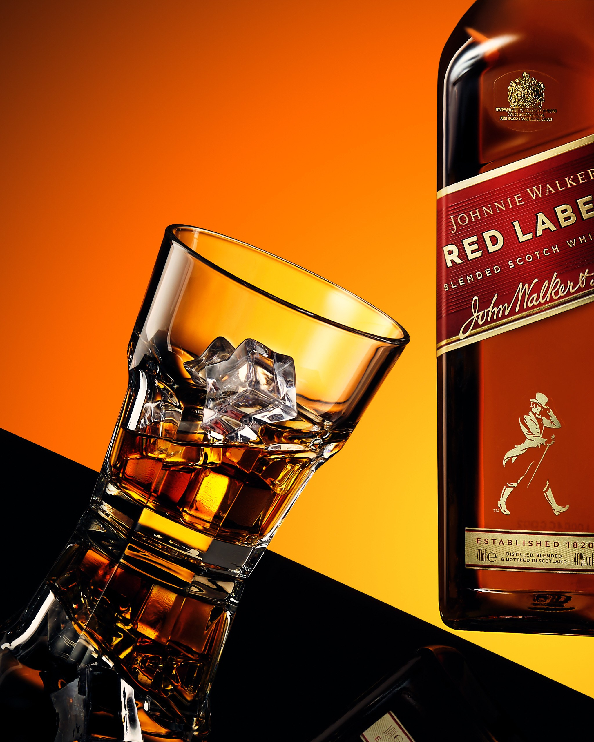 Виски «Johnnie Walker Red Label» с бокалом на чёрном фоне и всплесками