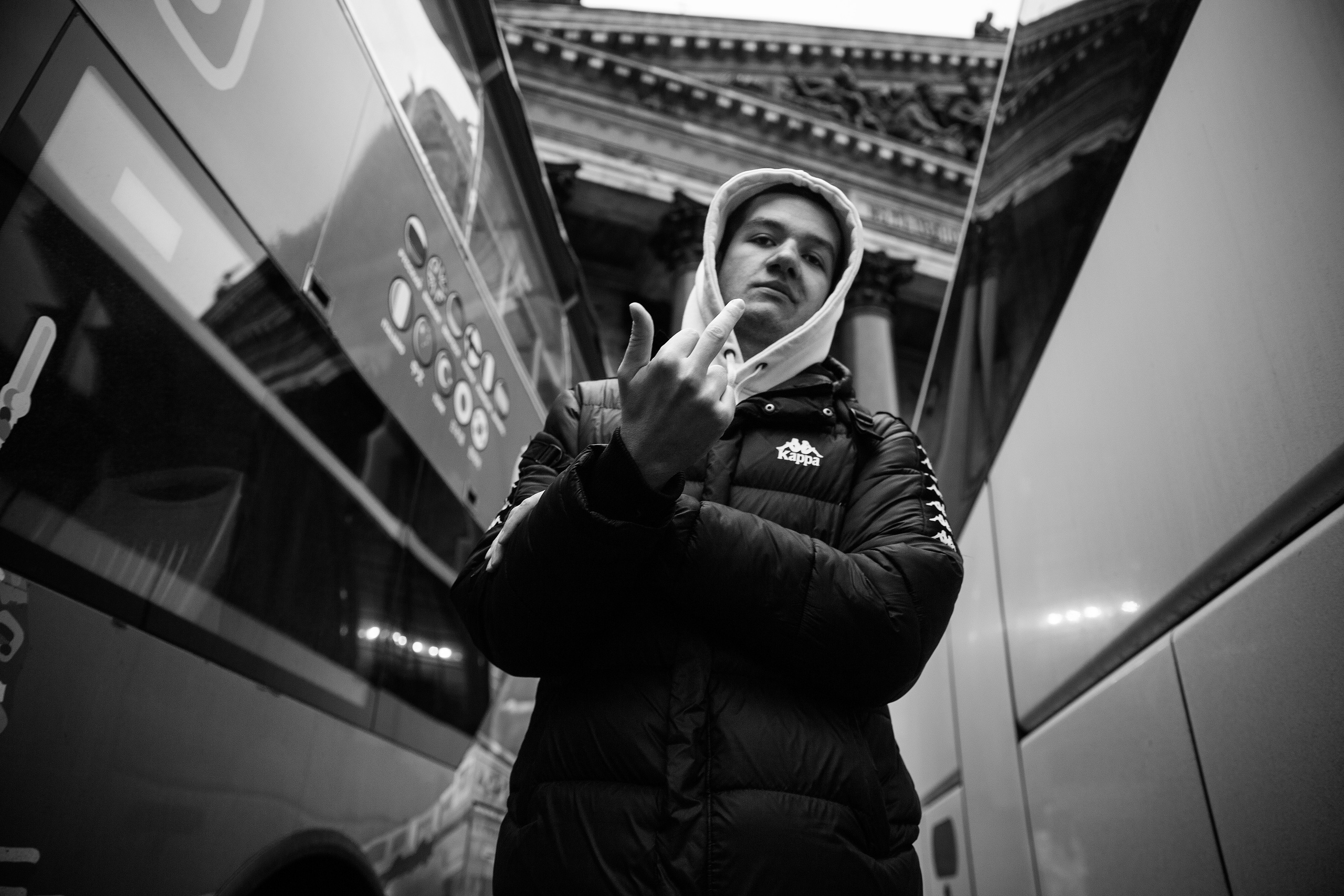 black and white portrait of a man standing between two buses
