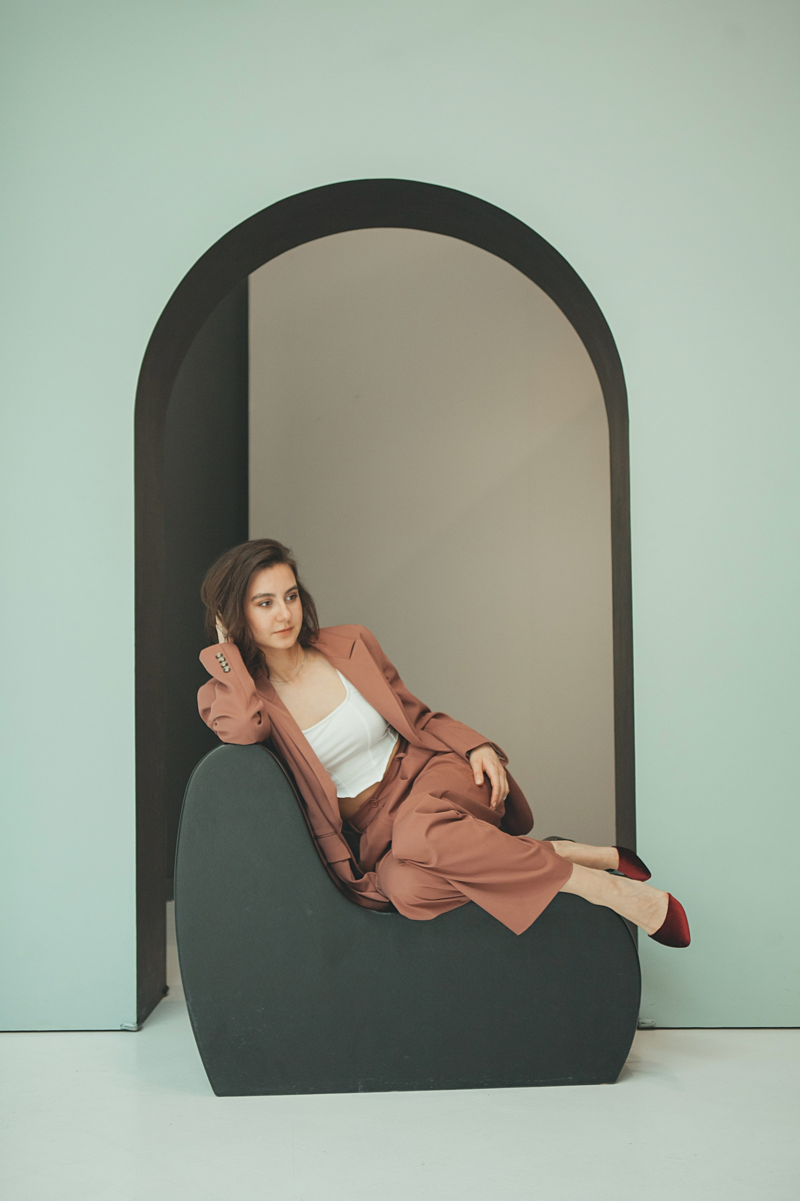 Девушка лежит на фоне арки на стуле в стиле хайтек