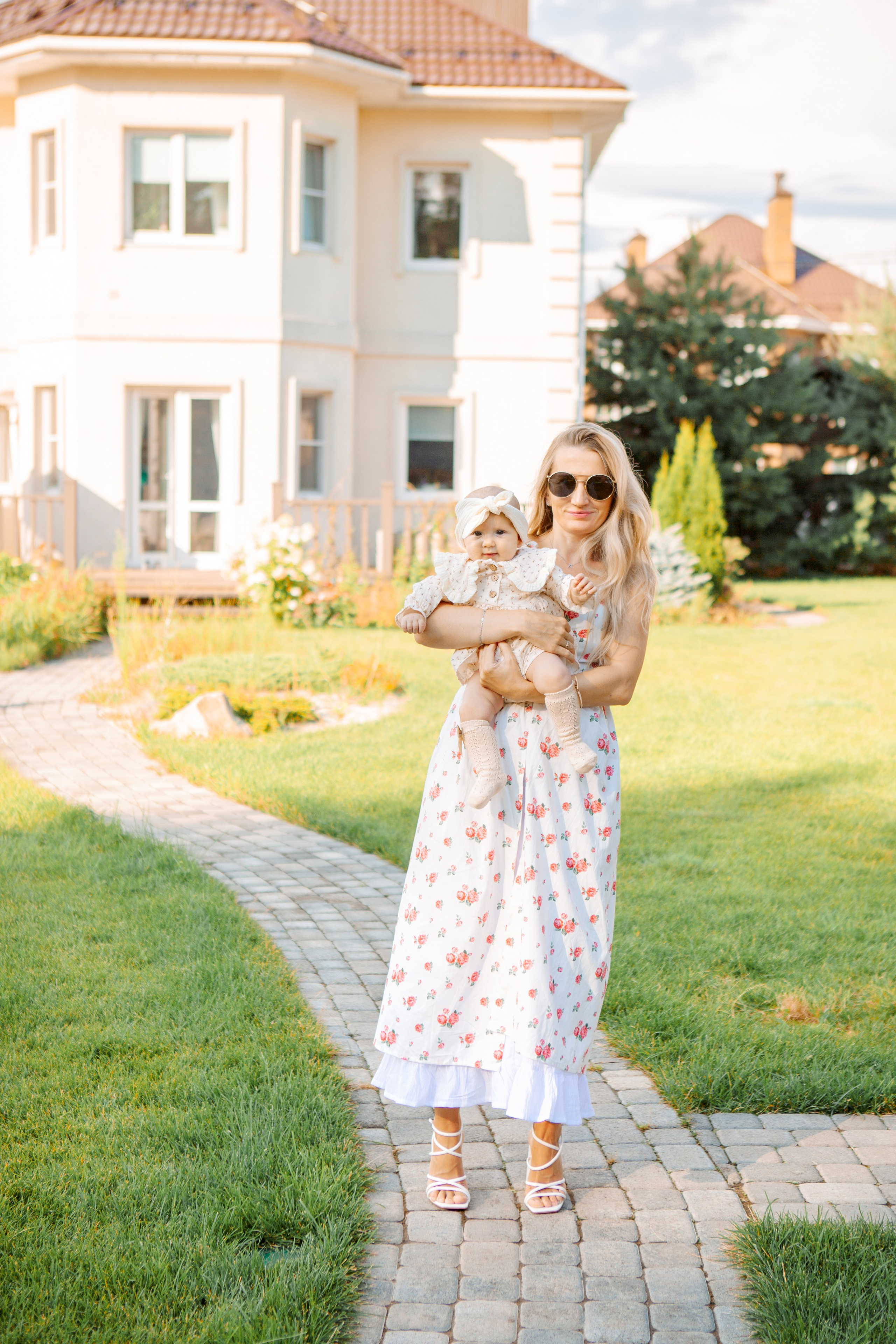 Мама с младенцем на фоне своего дома позирует.