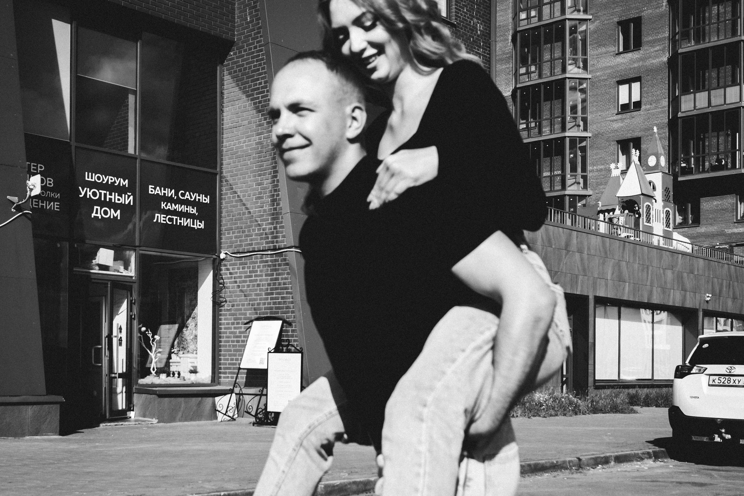 Молодая пара мужчина и девушка дурачатся в городских локациях в черных футболках и синих джинсах, лав стори для влюбленной пары на кануне свадьбы