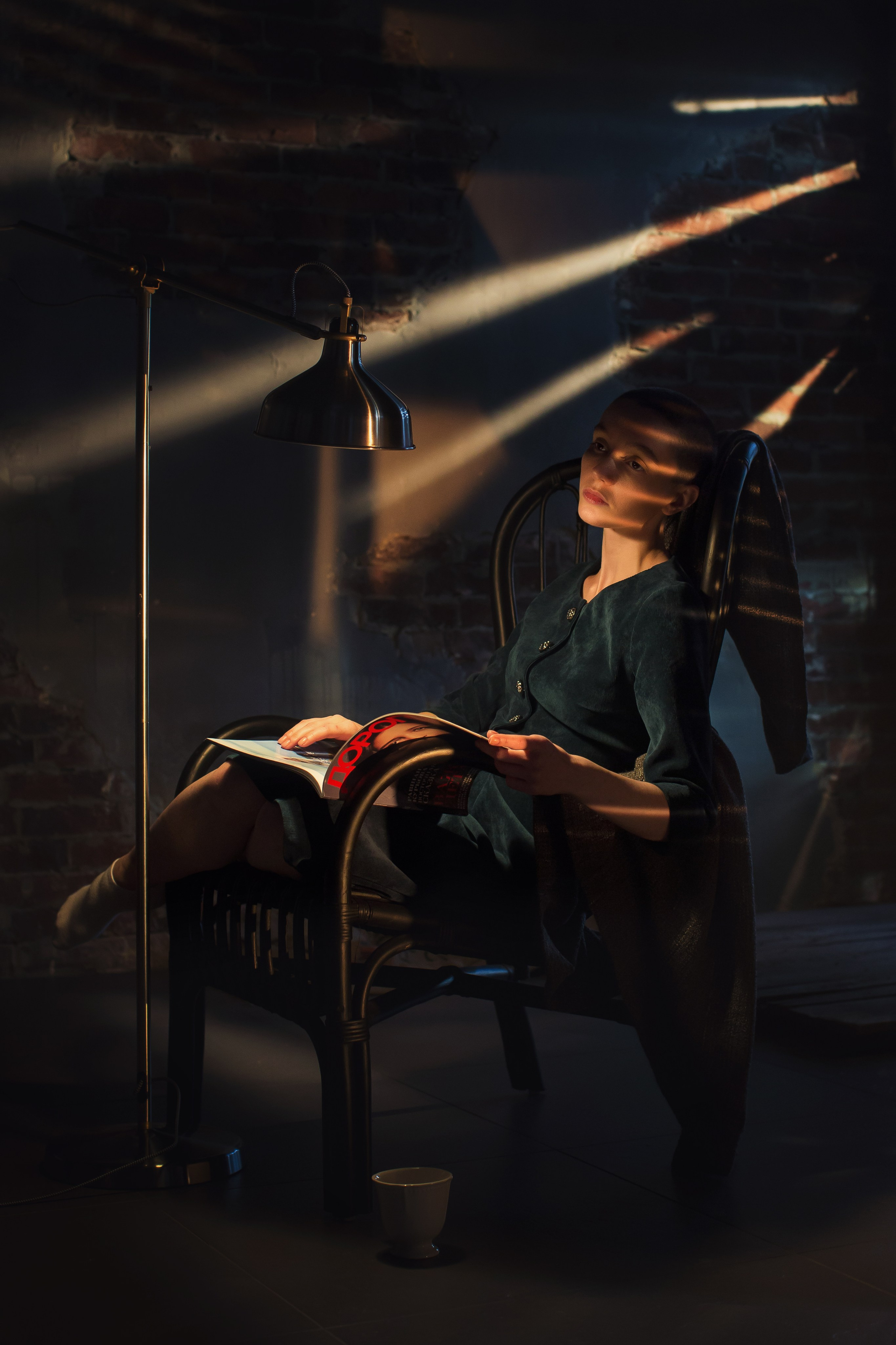 лысая девушка сидит в кресле с журналом на нее светят красивые лучи света