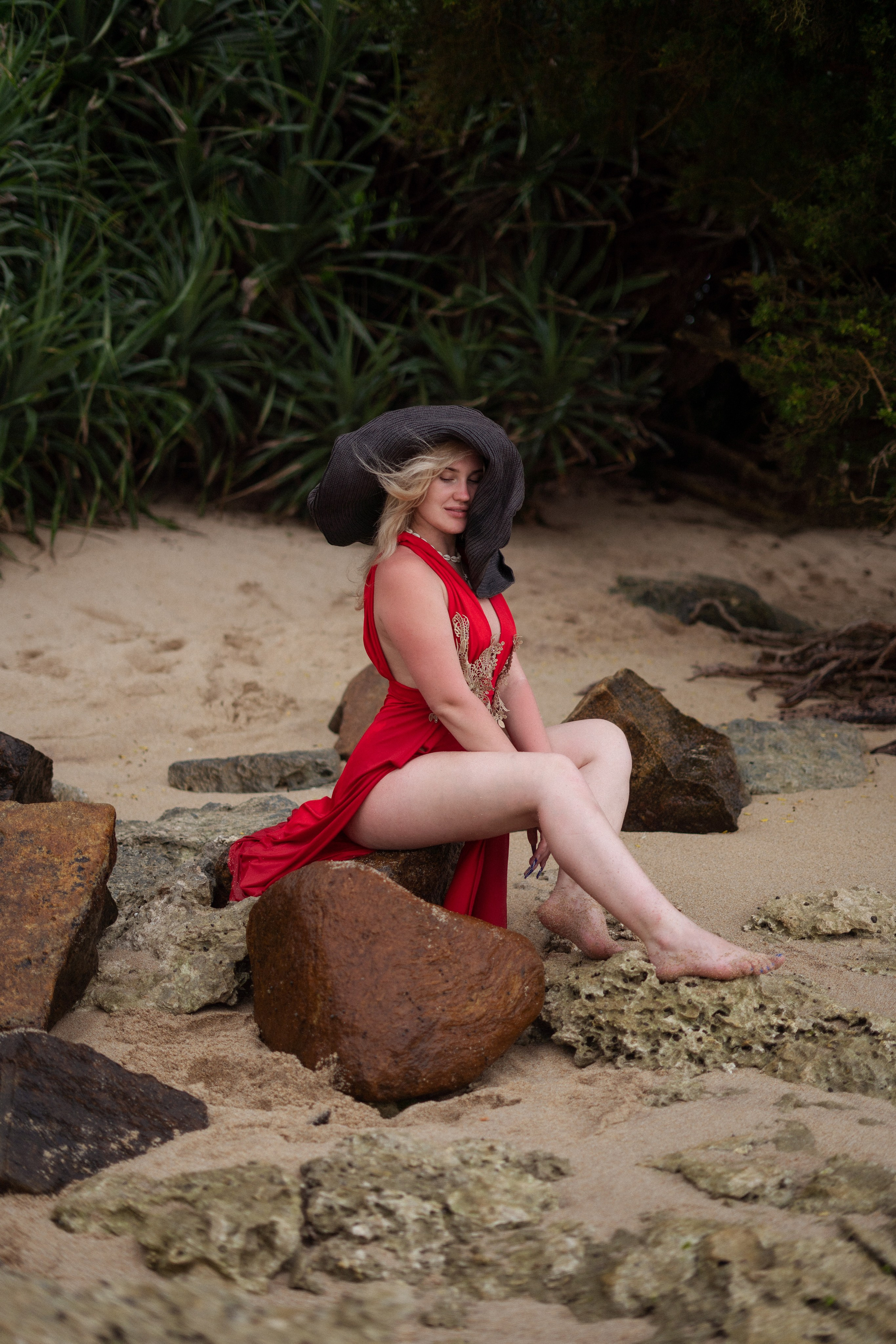 a beautiful blonde in a red dress posing by the ocean