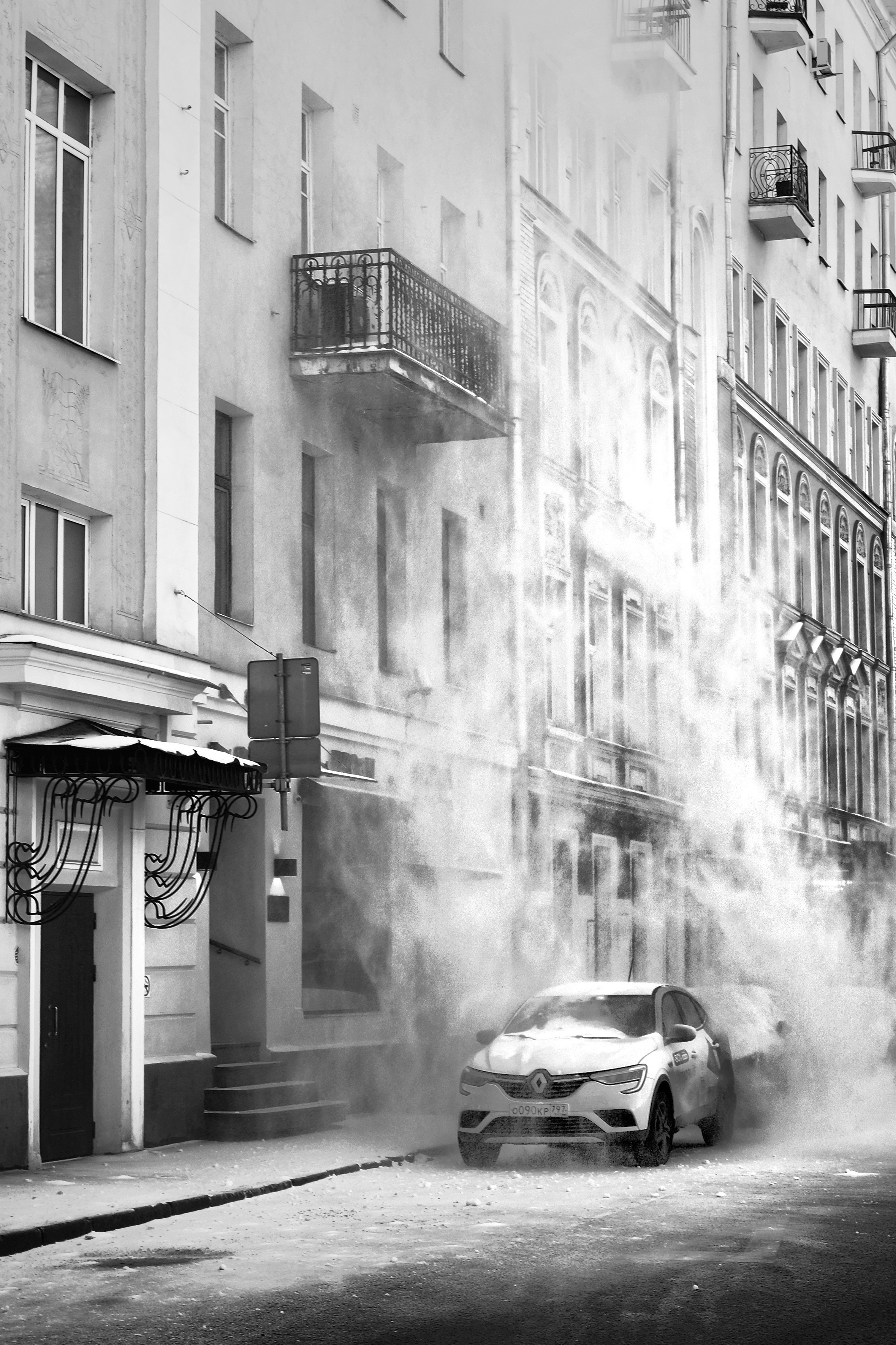 Снег падает на машину во время чистки крыши на Патриарших прудах в Москве