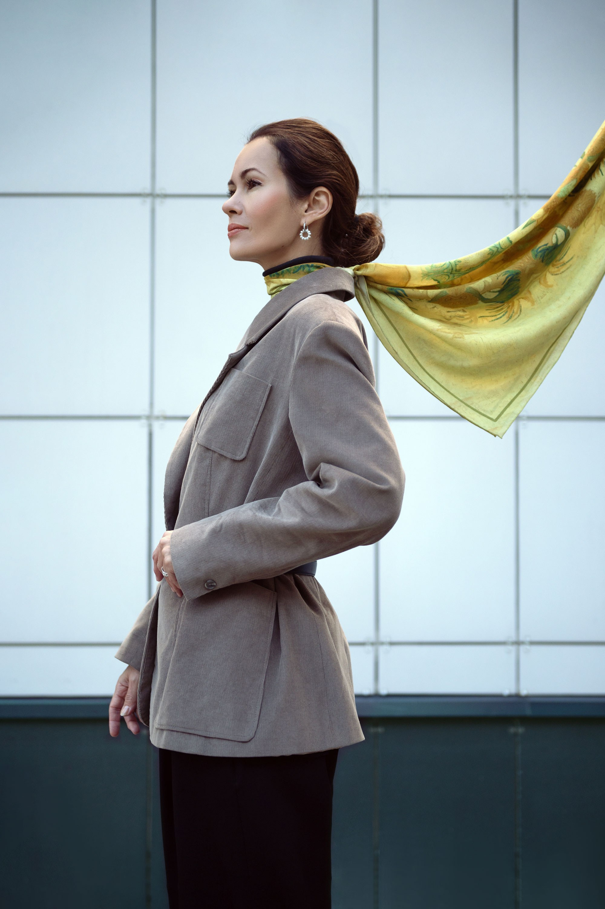 Девушка в пиджаке из велюра и черных брюках, на шее желтый шелковый платок. Съемка для бутика женской одежды. Свет падает сверху, красиво подсвечивая шелковый платок и скулы модели.