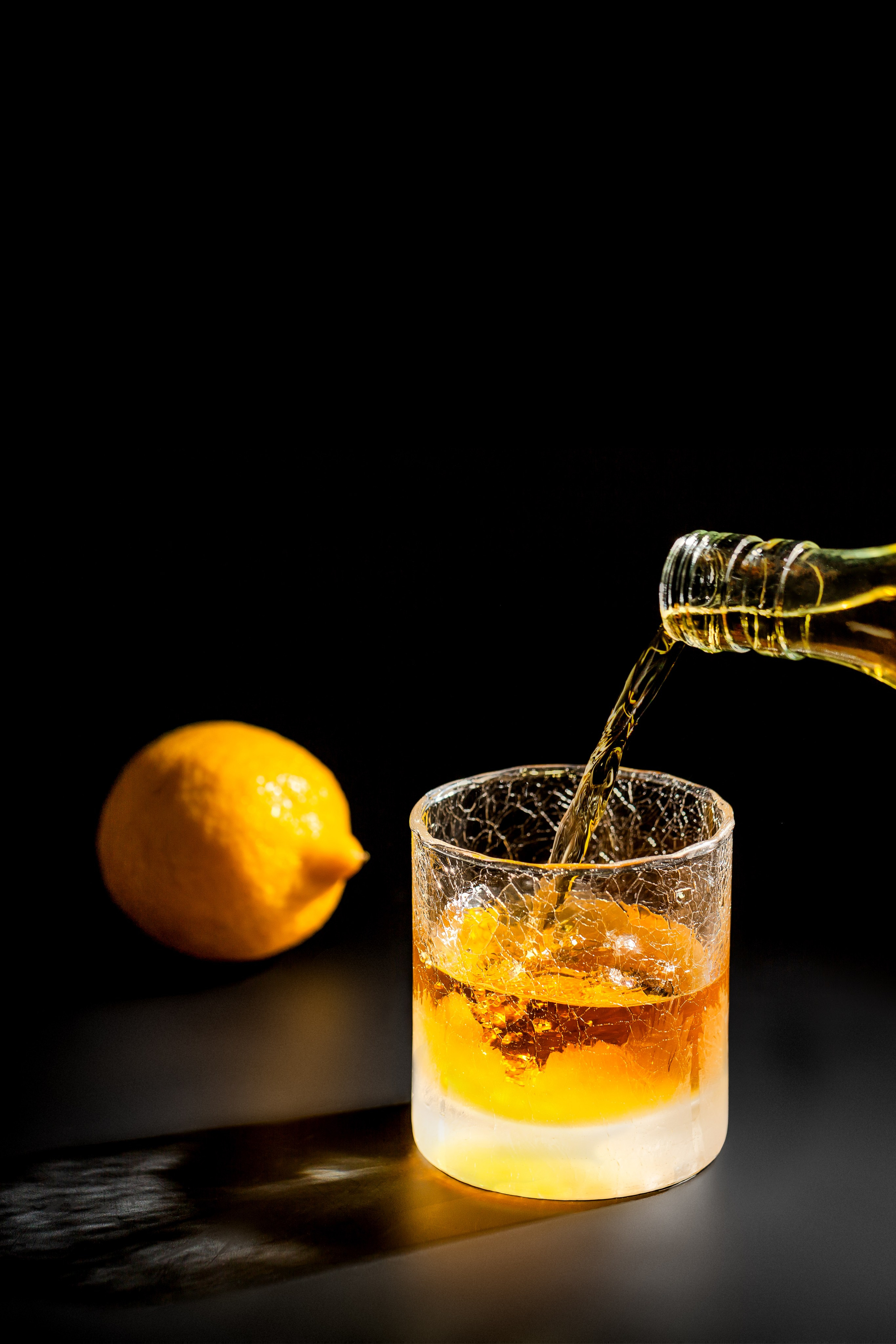 Виски наливают в красивый бокал на темном фоне