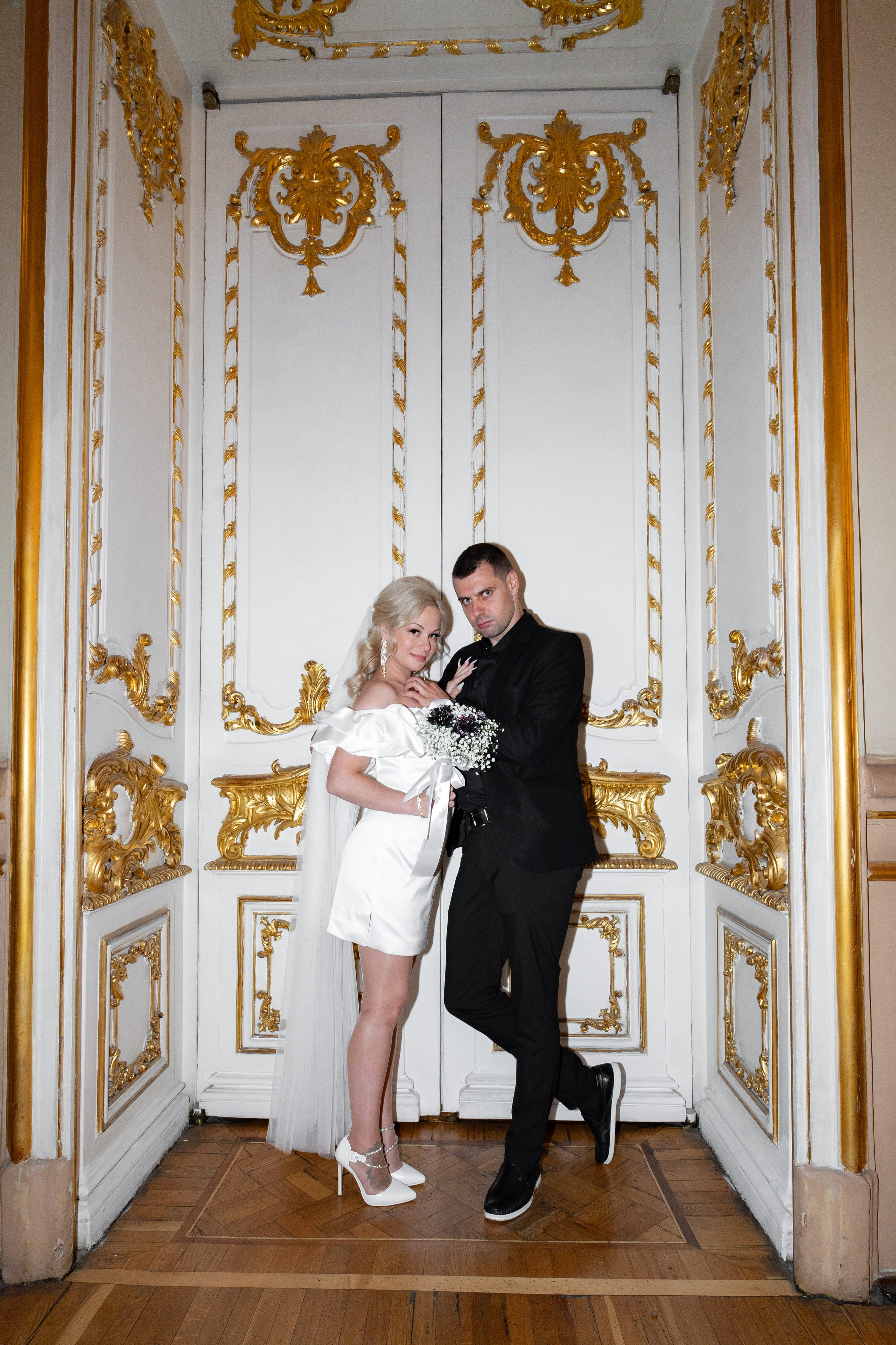 жених и невеста красиво стоят перед дверью белого цвета во дворце бракосочетания №1 в Санкт-Петербурге