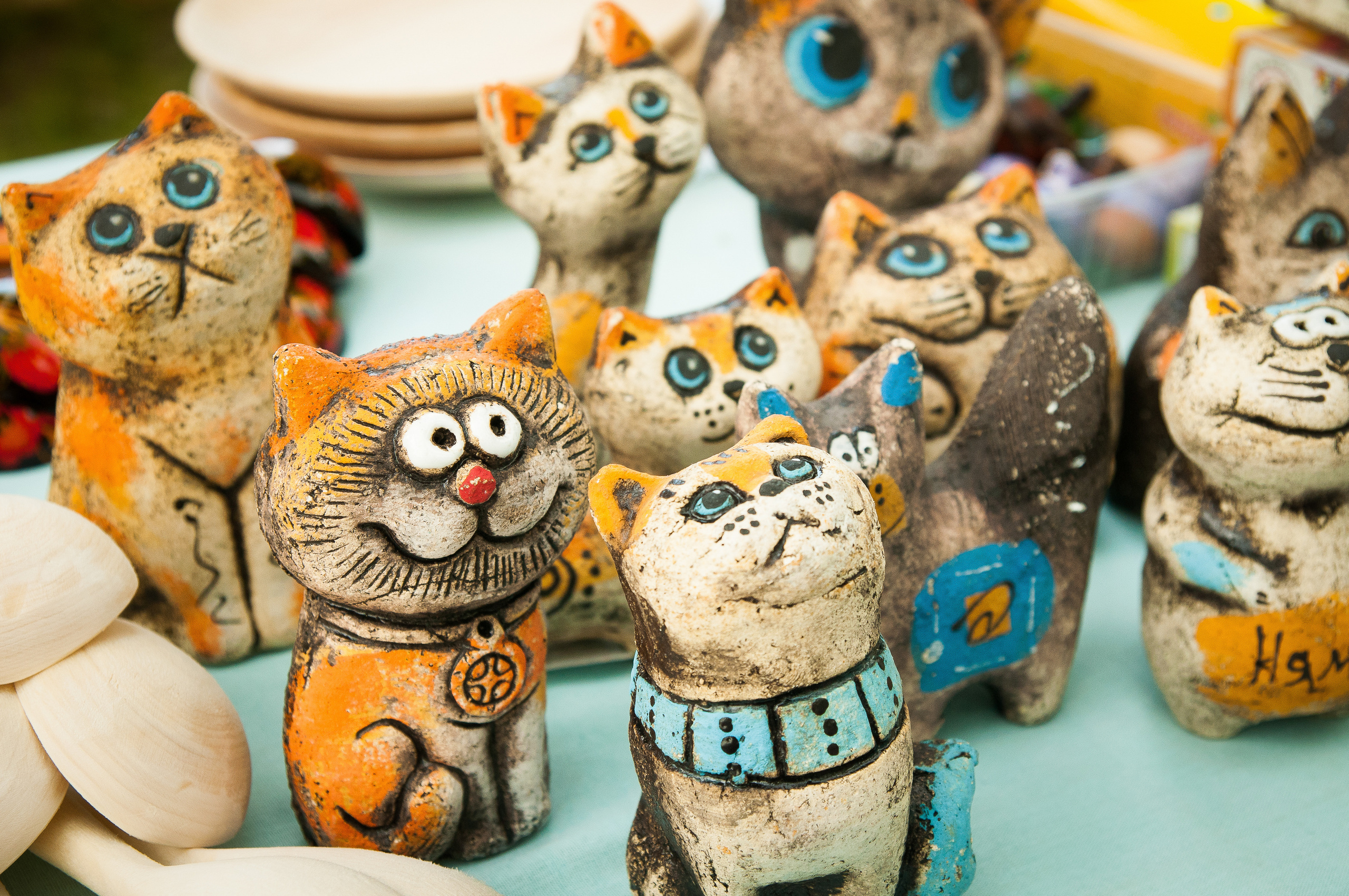 Расписные глиняные фигурки котов стоят на столе