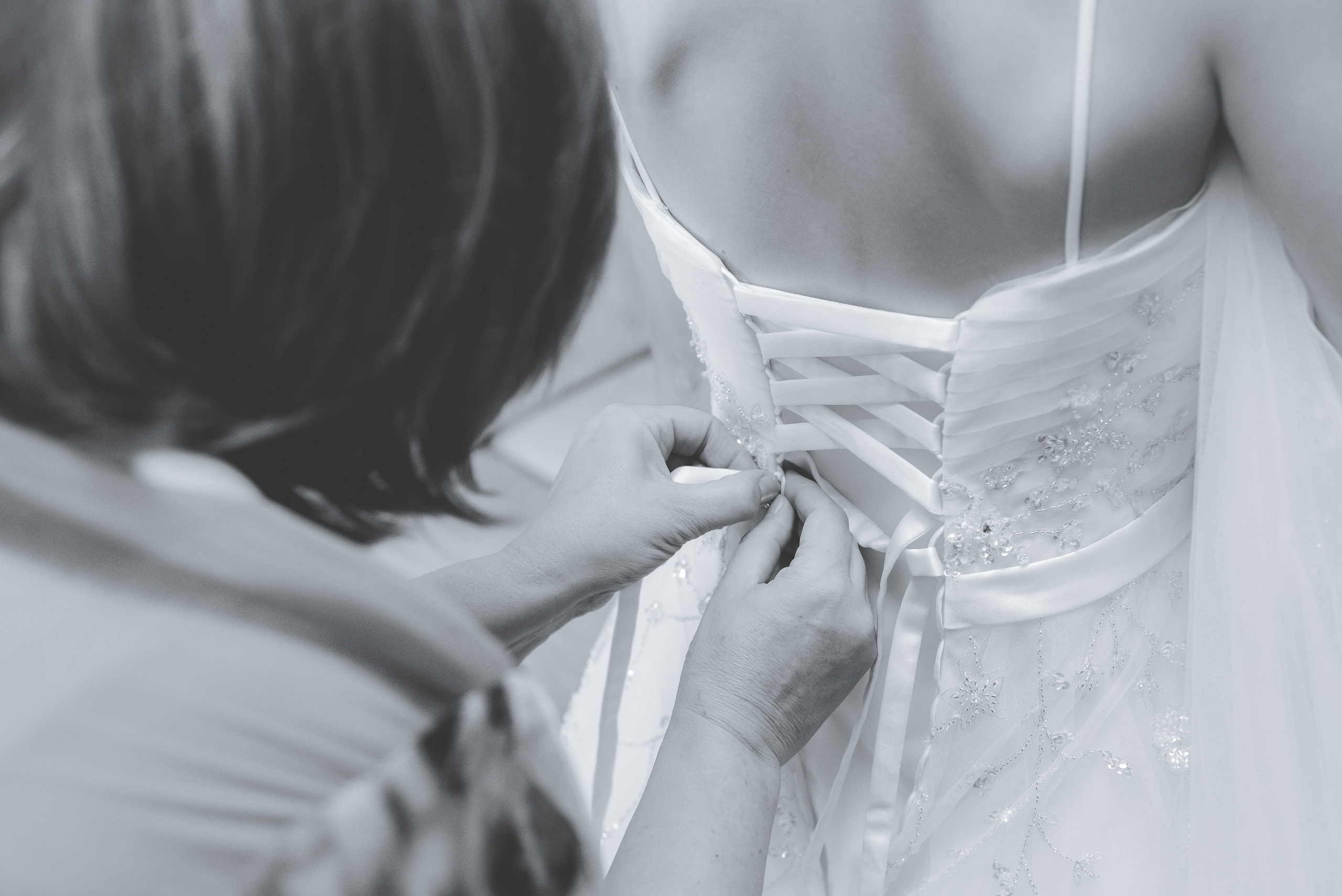 Подруга невесты затягивает корсет на платье невесты