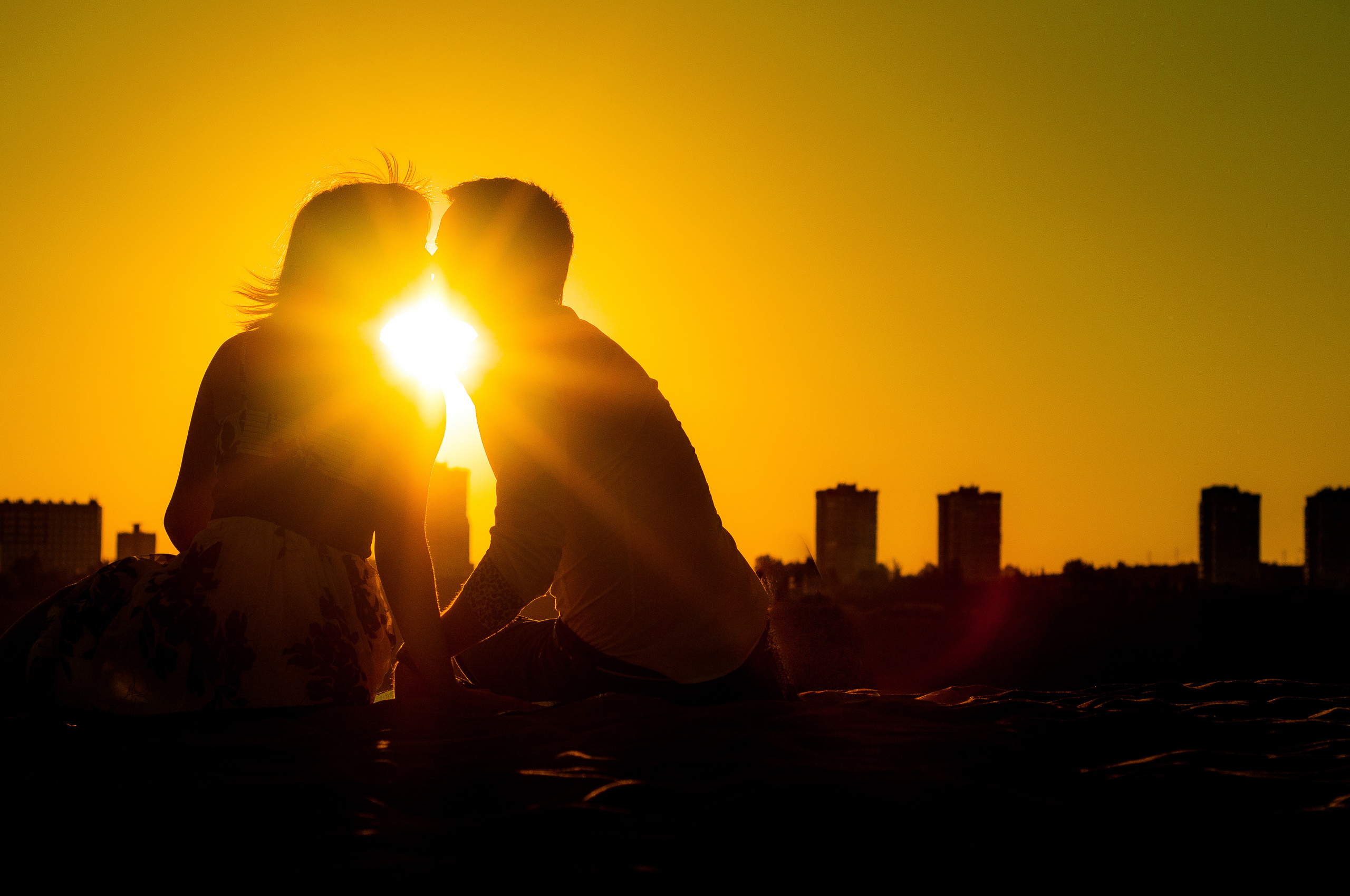 Влюбленная пара целуется на закате на фоне солнца