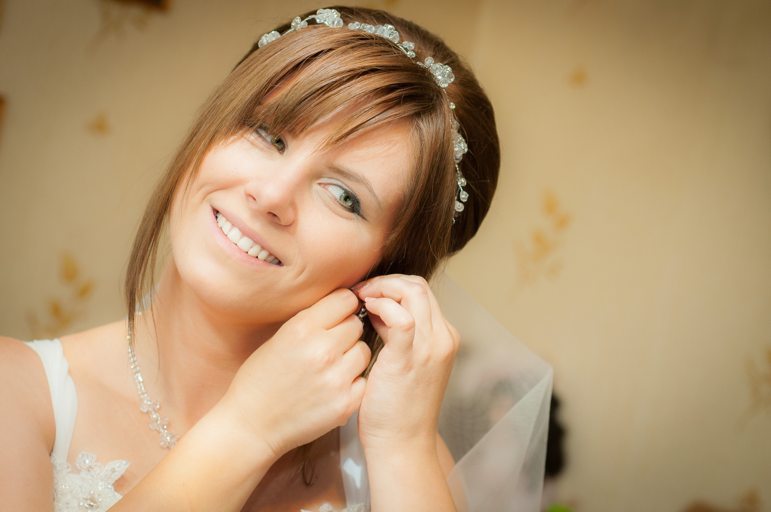 Невеста надевает серьги и улыбается