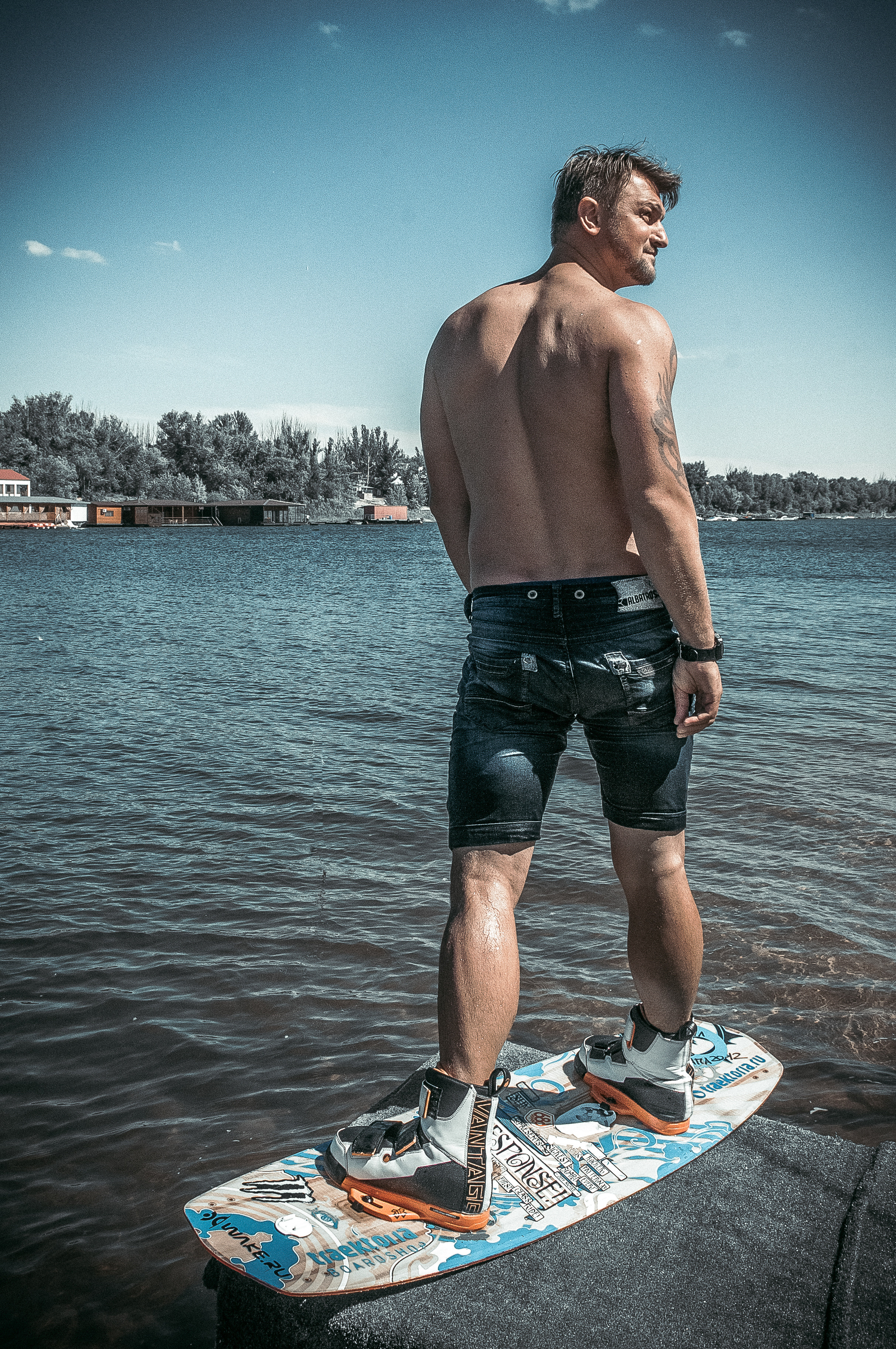 Человек стоит на вейкборде и оглядывается назад