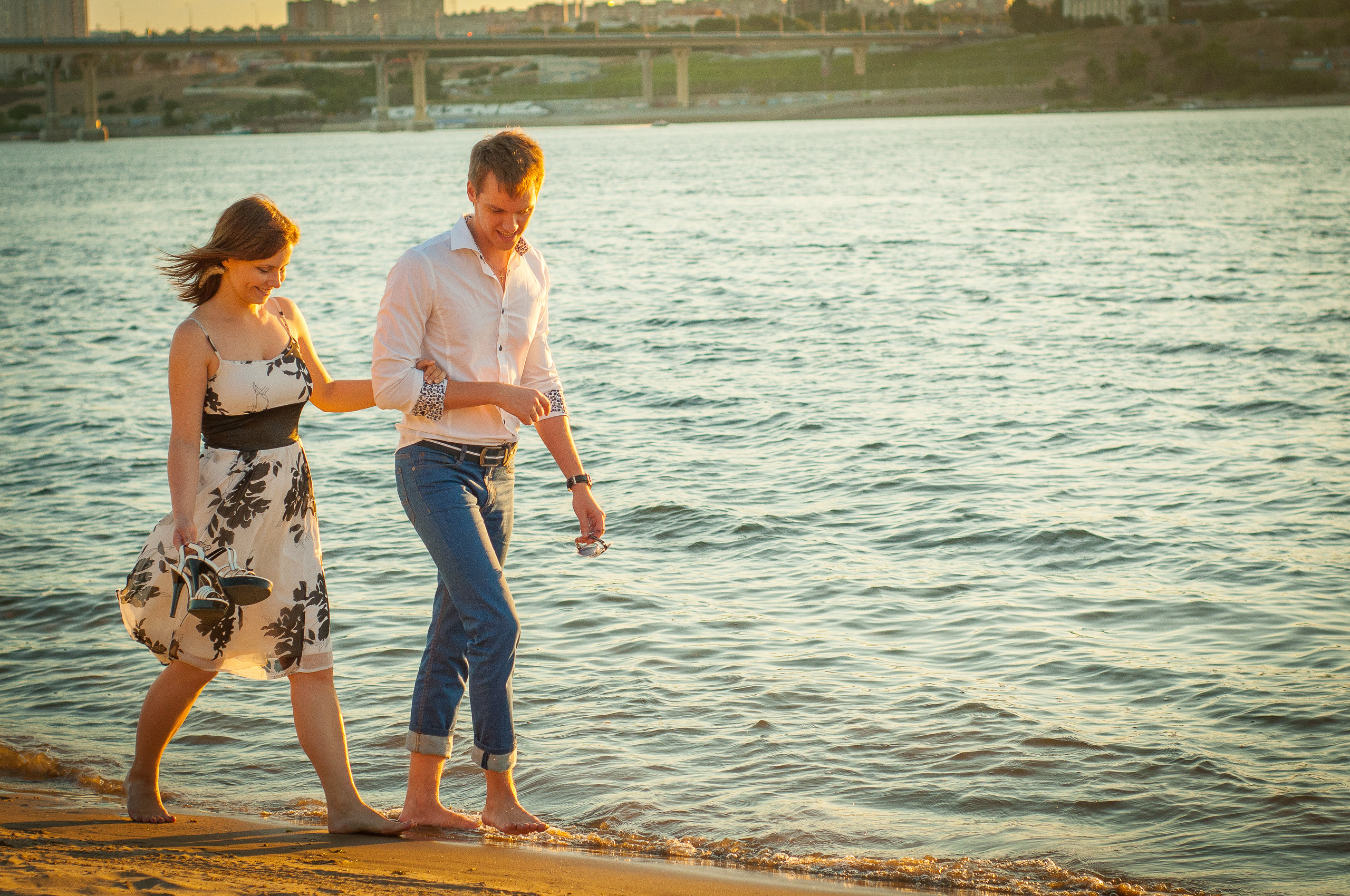 Парень с девушкой идут босиком по берегу реки