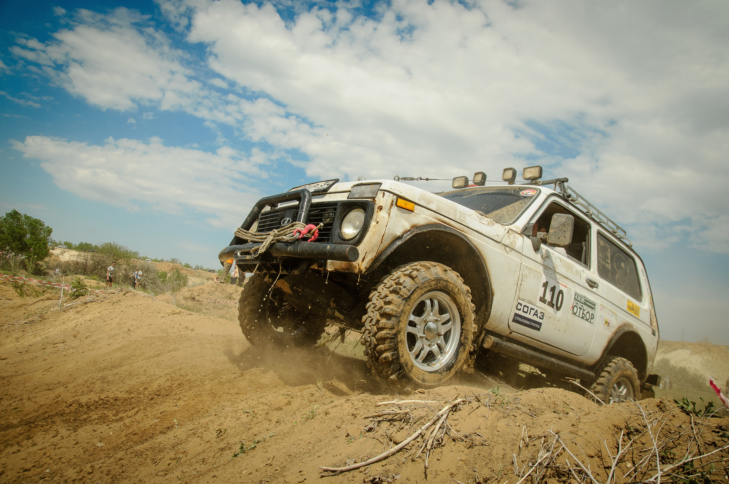 Автомобиль Нива заезжает в гору, поднимая пыль из-под колёс