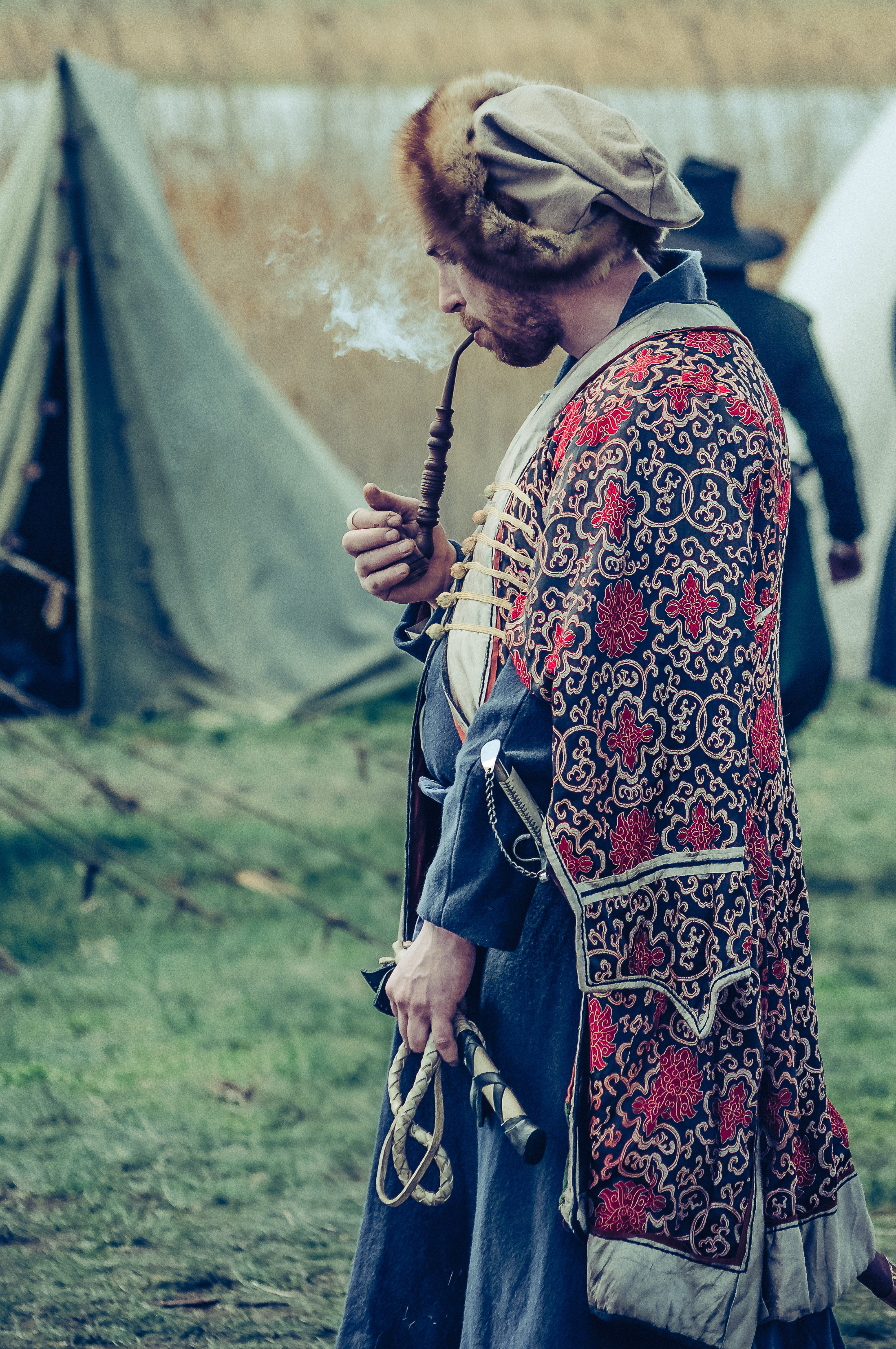 Мужчина в исторической одежде курит трубку