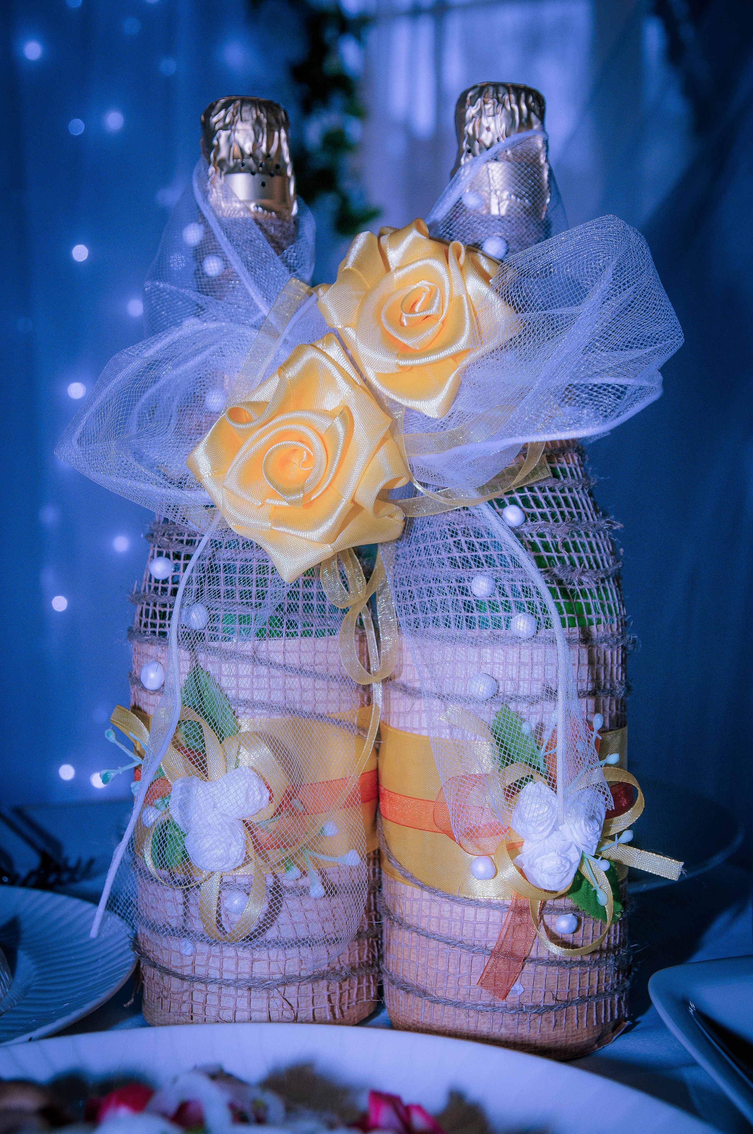 Две свадебных бутылки шампанского с бежевыми розами стоят на столе