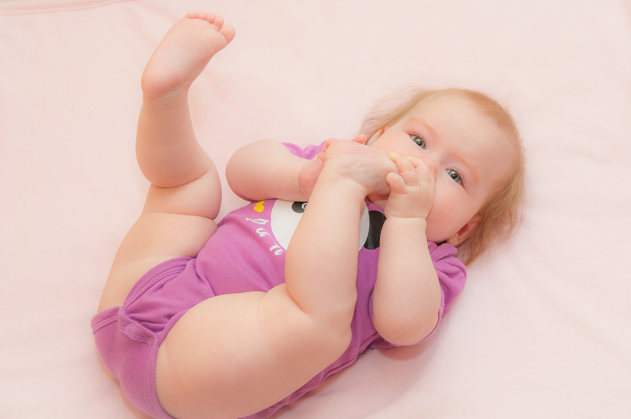 Ребёнок лежит с поднятыми ножками