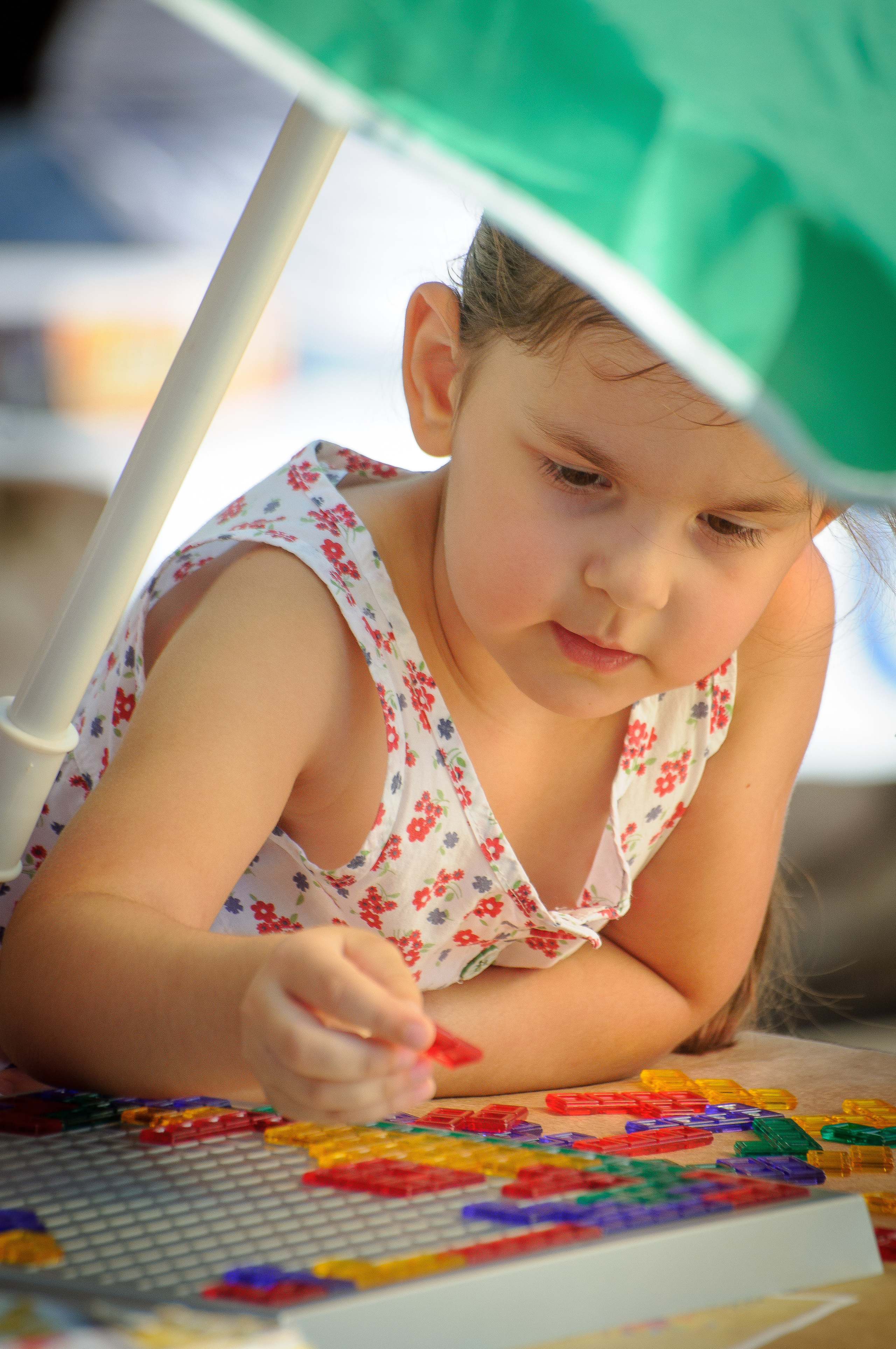 Ребёнок под зелёным зонтом играет в настольную игру