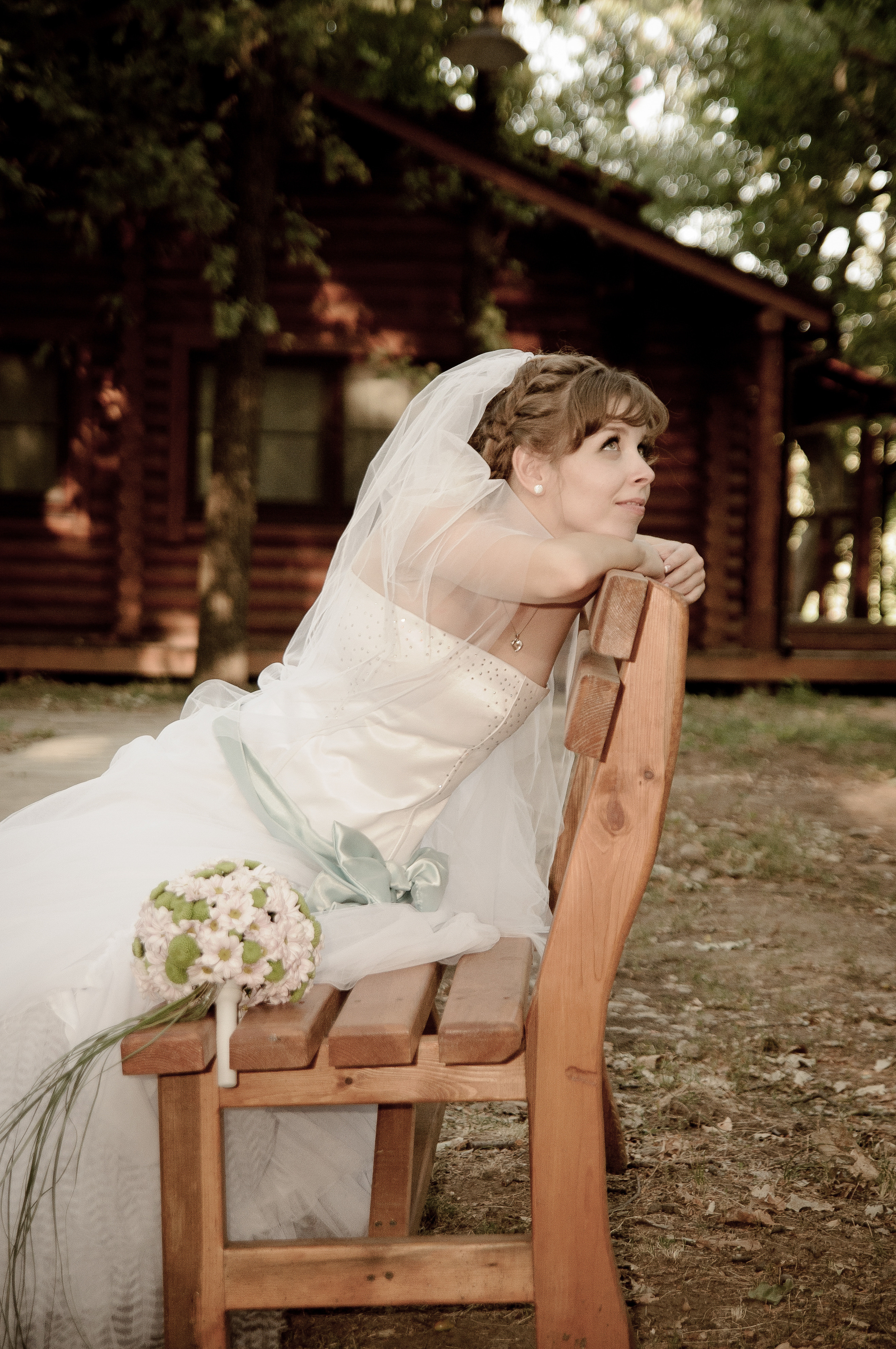 Невеста сидит на деревянной скамейке