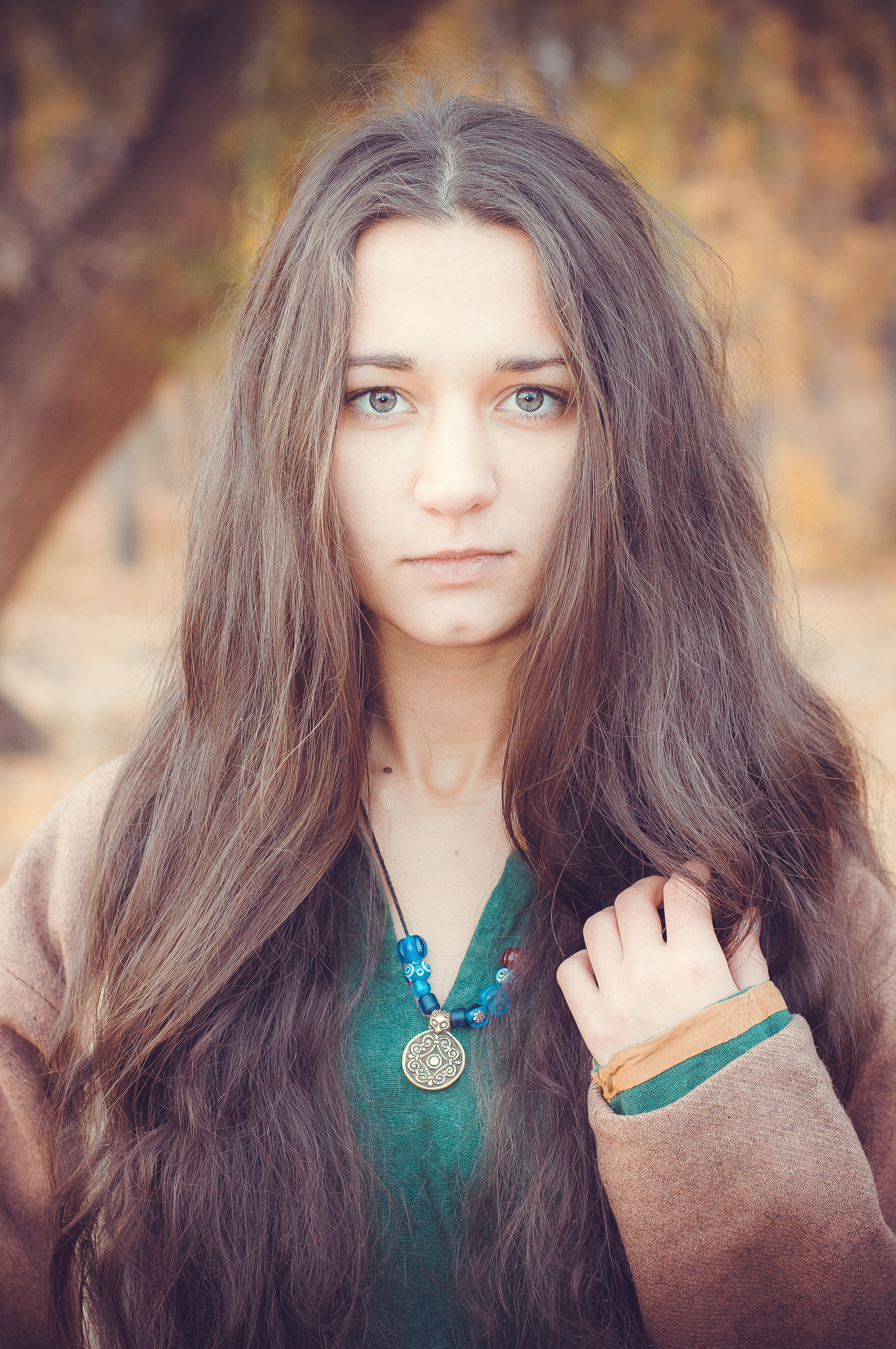 Девушка в коричневом платье с кулоном на шее