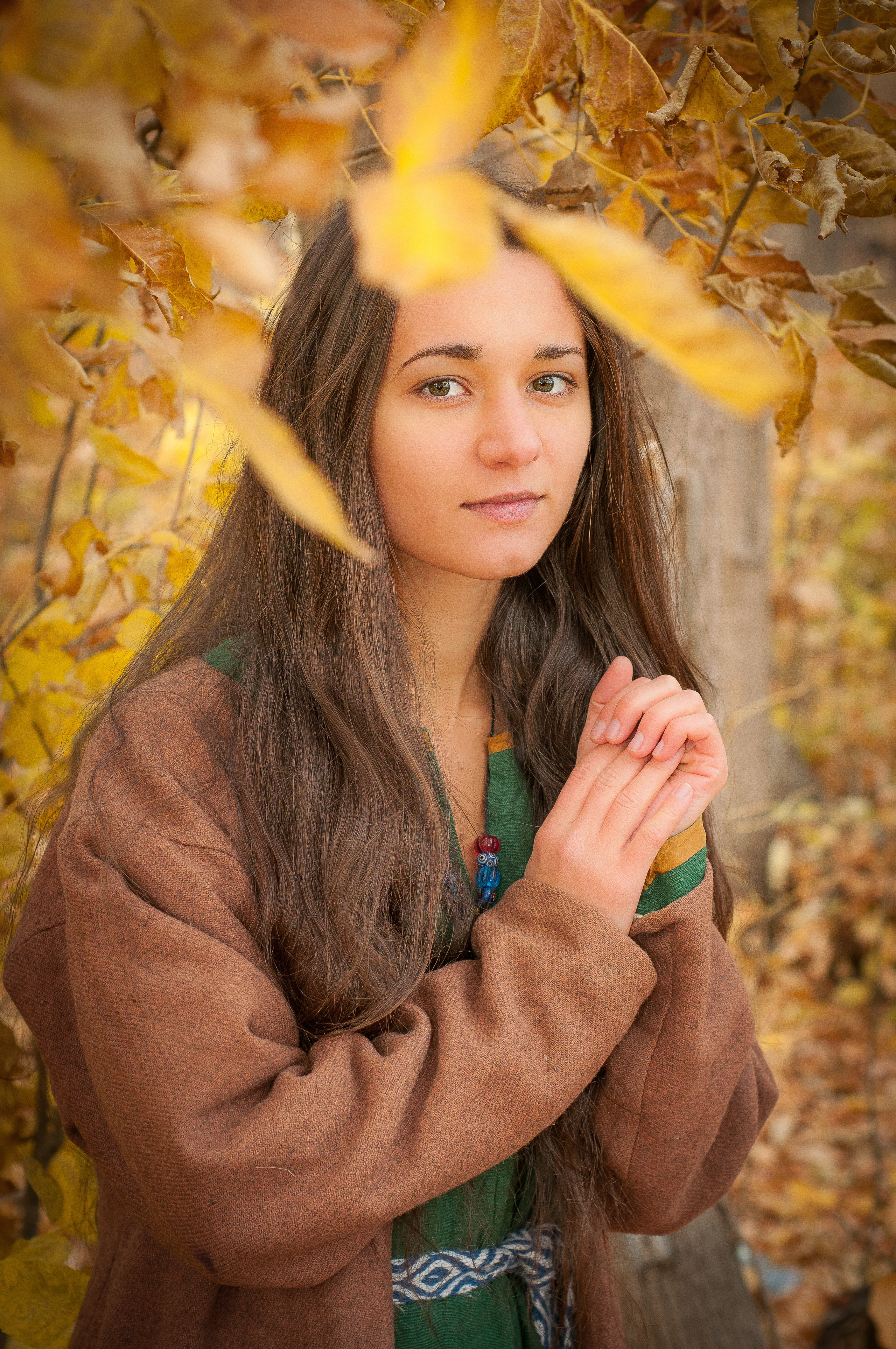Девушка в коричневой одежде в осеннем лесу с желтыми листьями