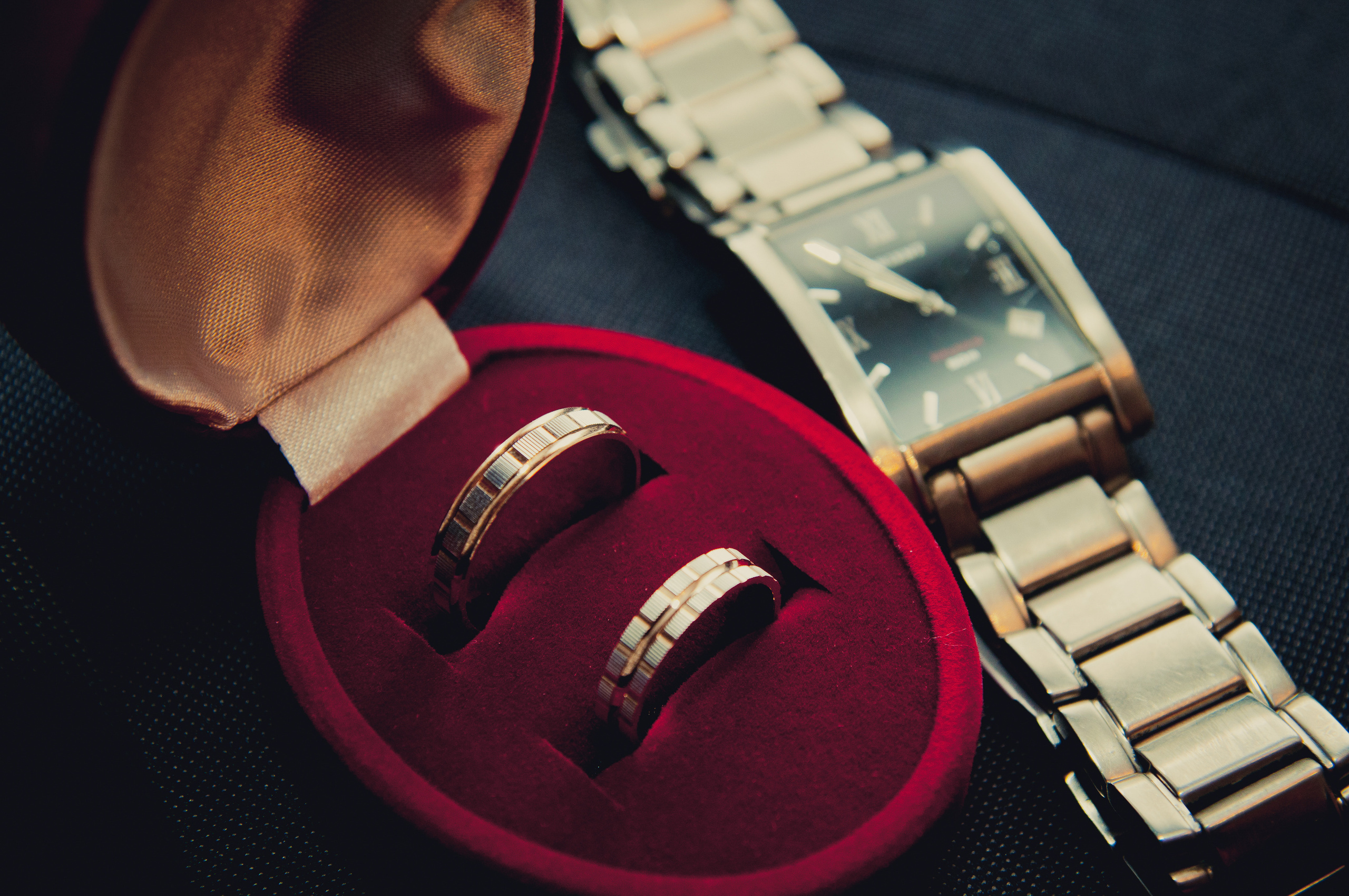 Обручальные кольца в футляре и часы лежат на столе