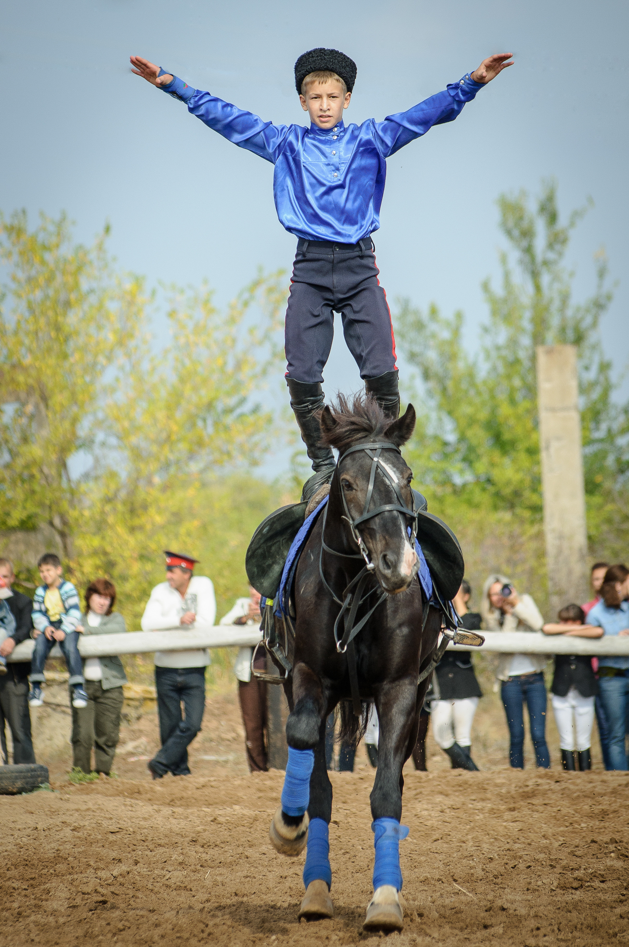 Мальчик стоит на скачущем коне во время джигитовки