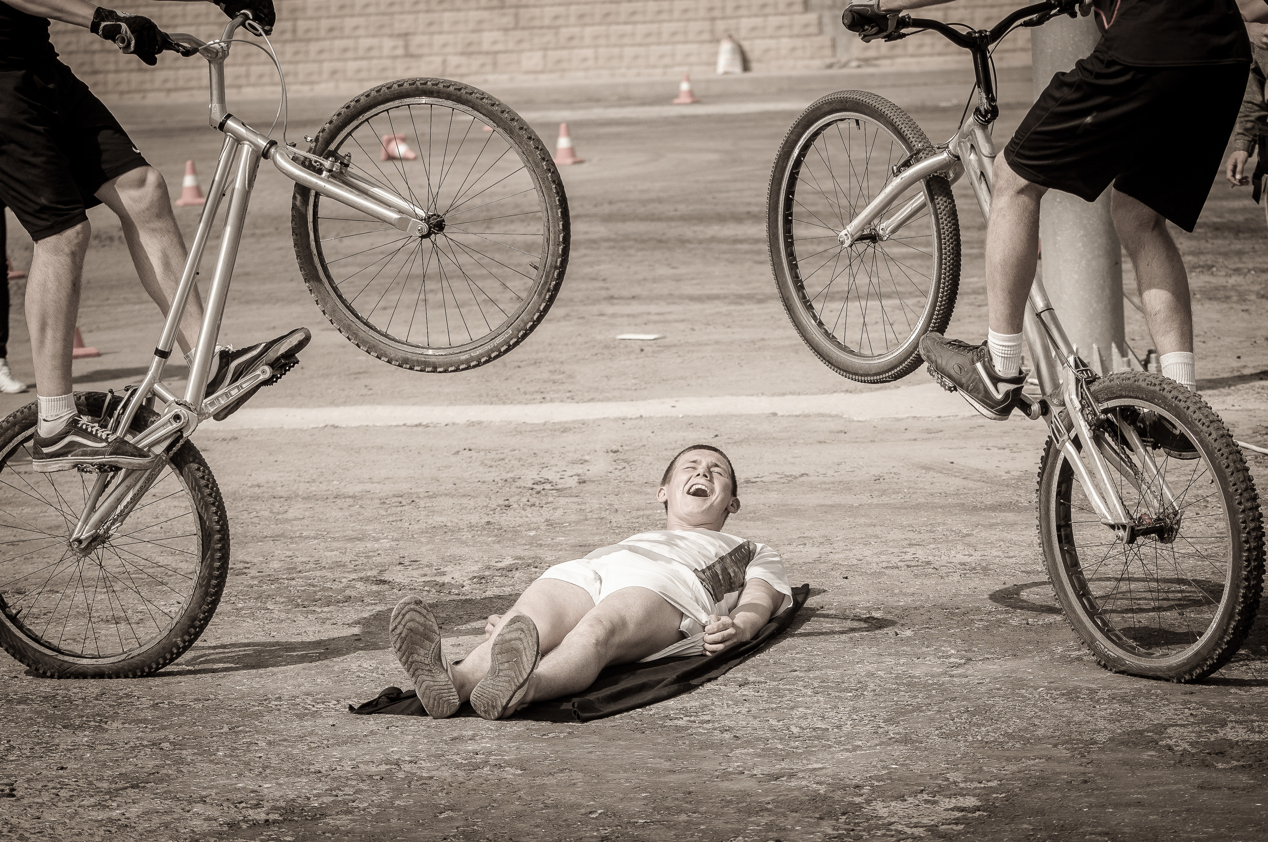 Два велосипедиста выполняют трюк над лежащем на земле человеком