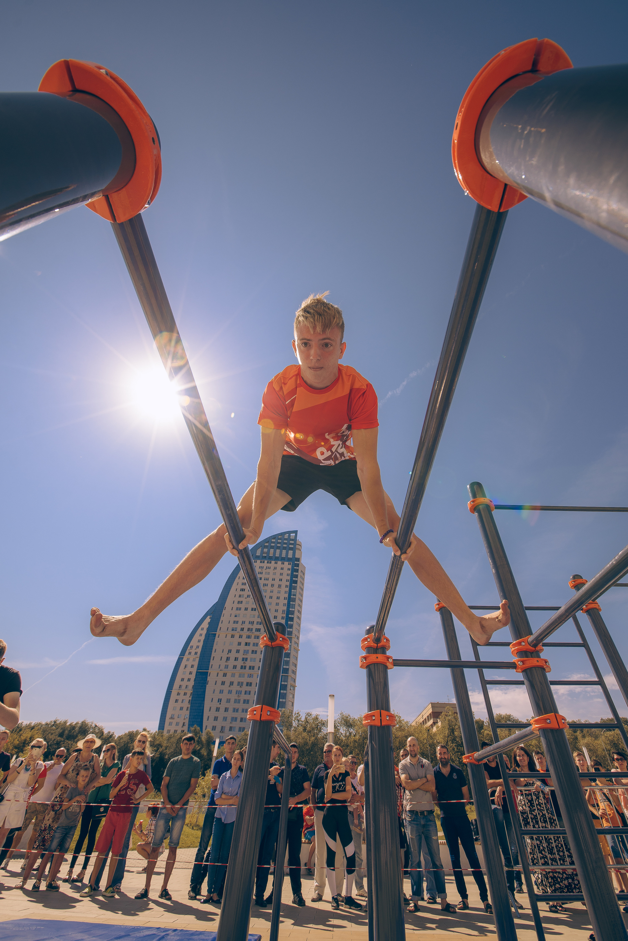 Соревнования по воркауту, парень делает стойку на брусьях
