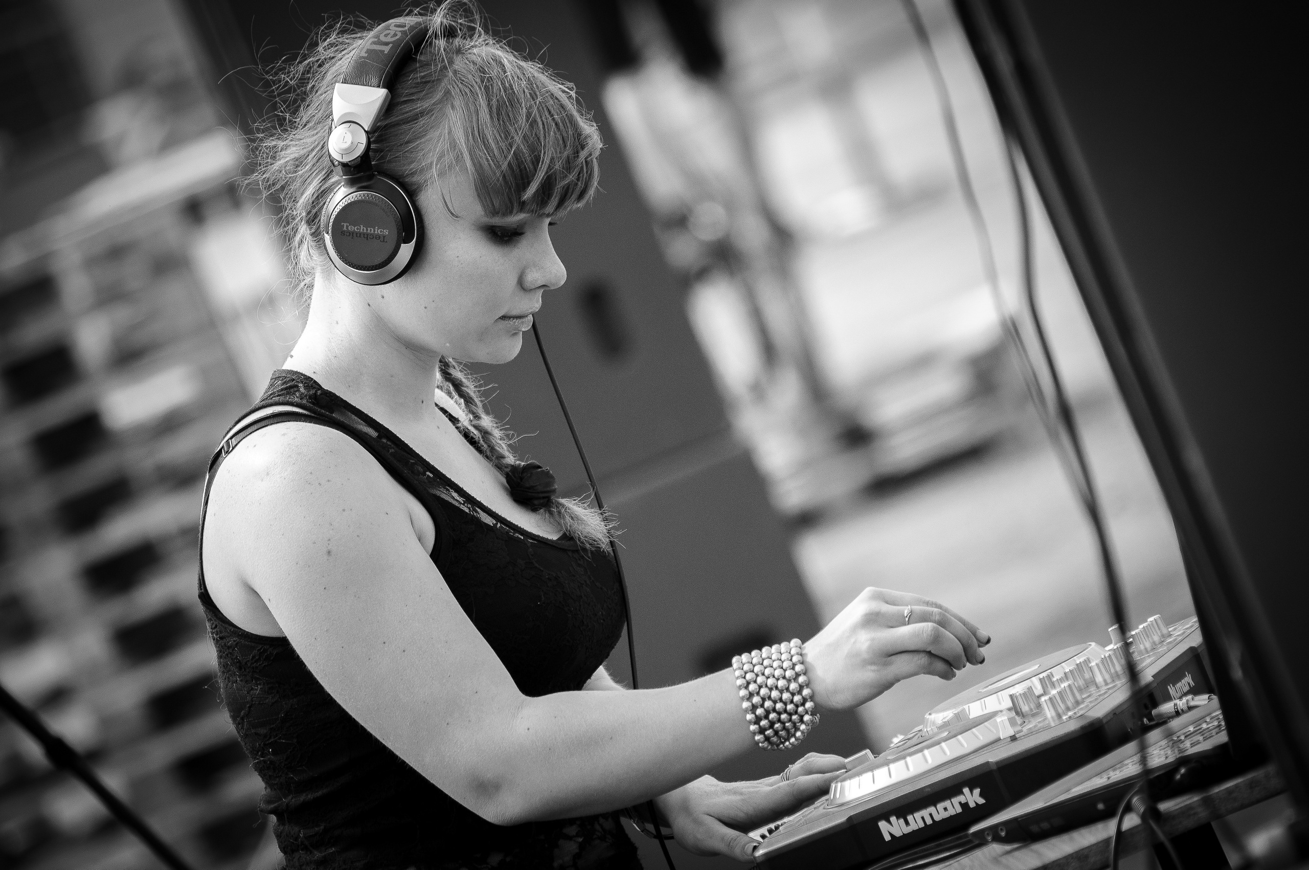 Девушка-диджей в наушниках играет музыку склонившись над микшером