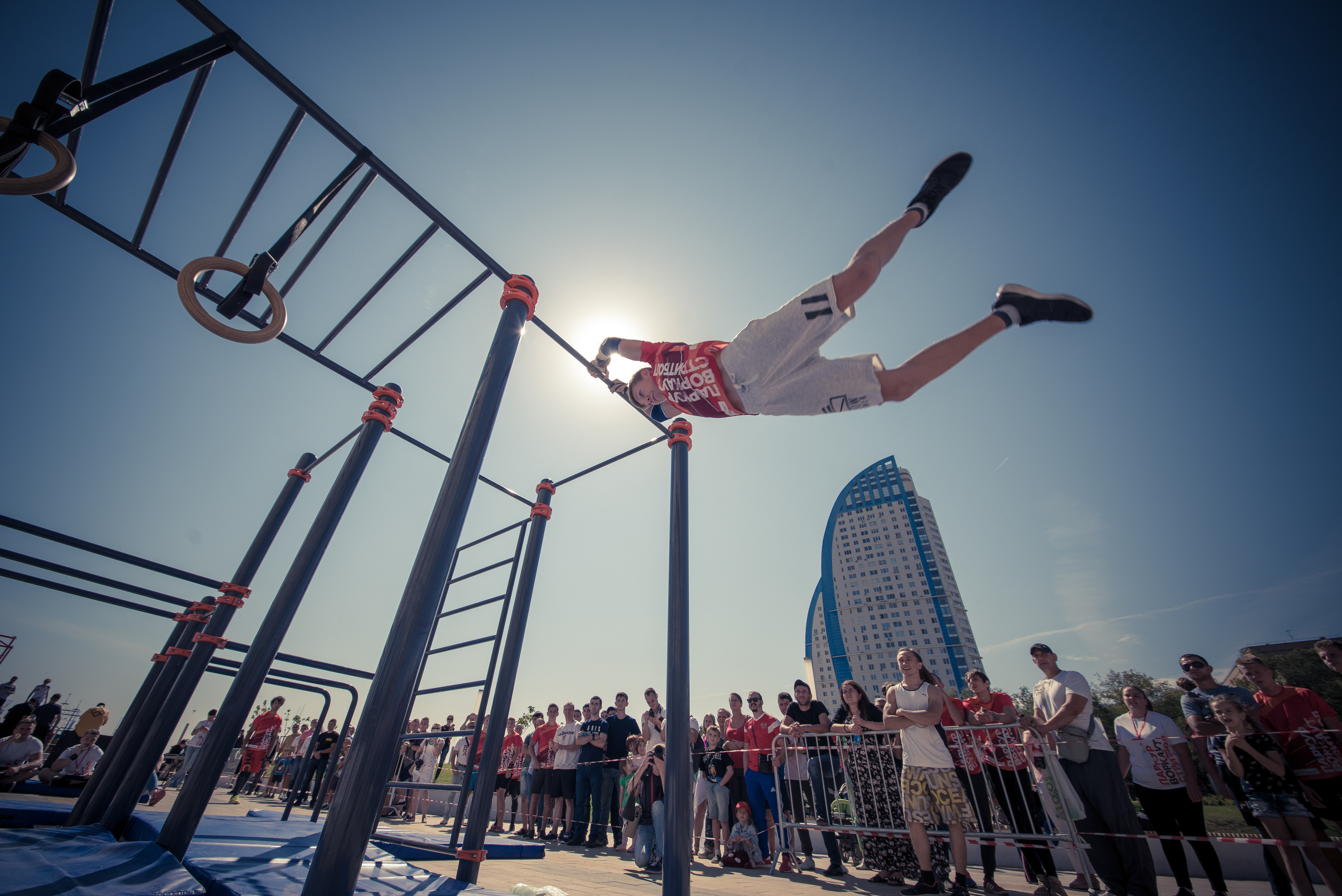 Мужчина совершает акробатический элемент на брусьях на соревнованиях по воркауту