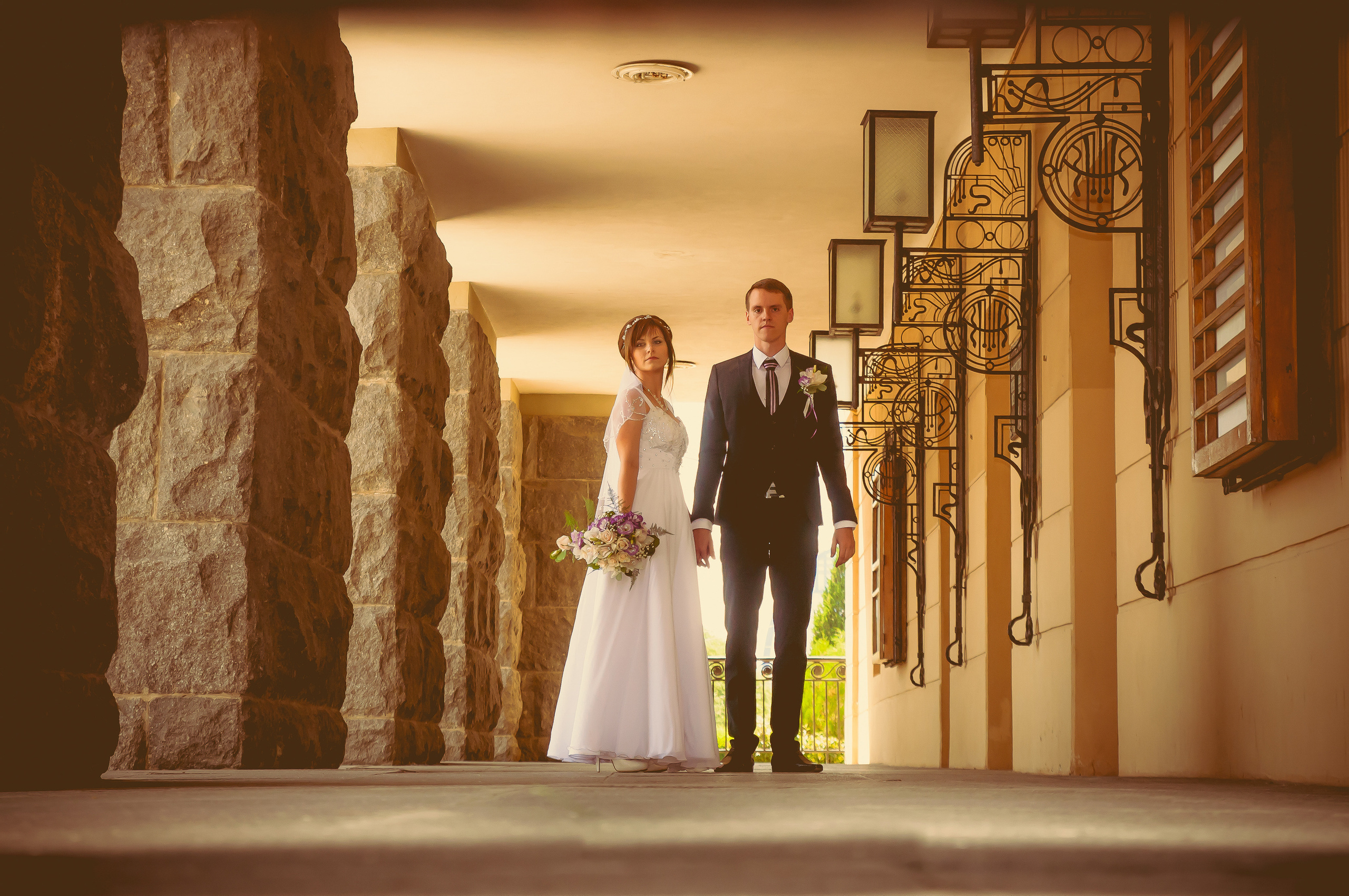 Жених и невеста идут вдоль колонн красивого здания театра