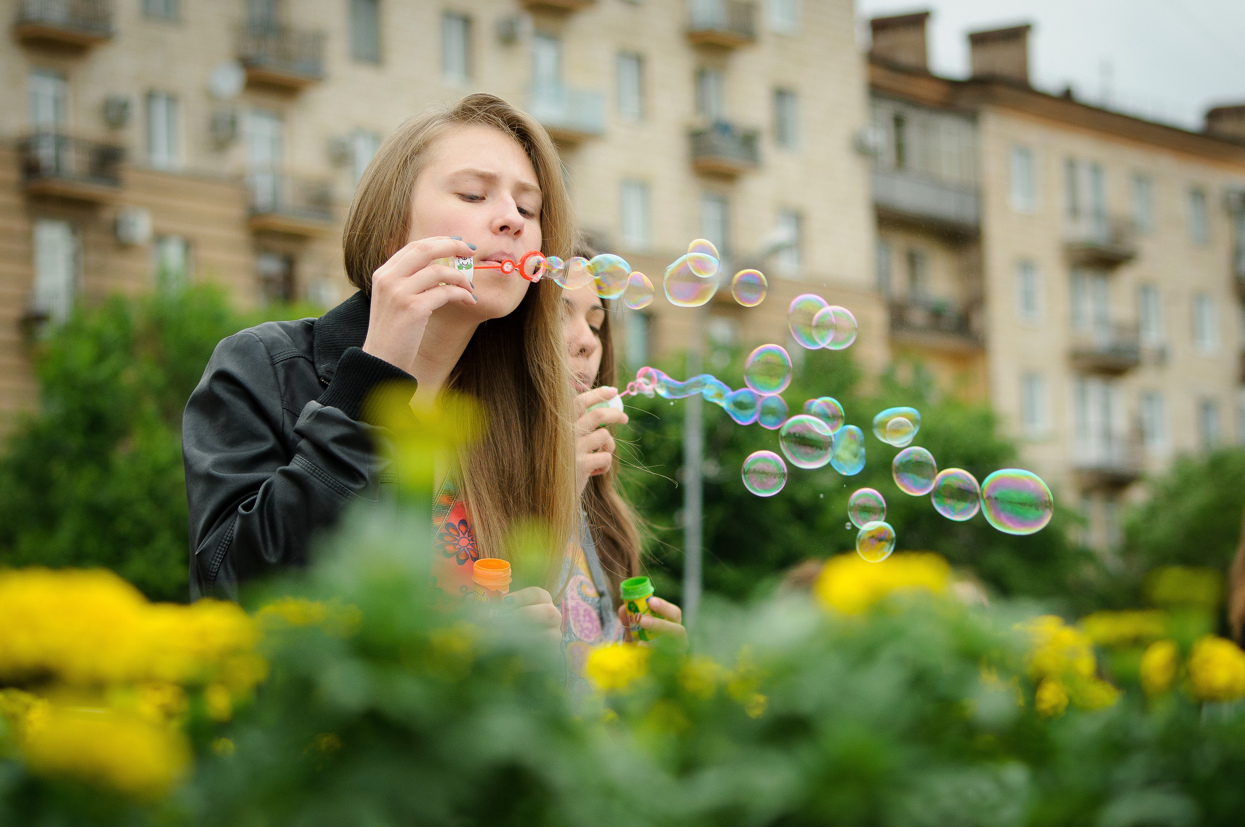 Девушка пускает мыльные пузыри около жёлтых цветов