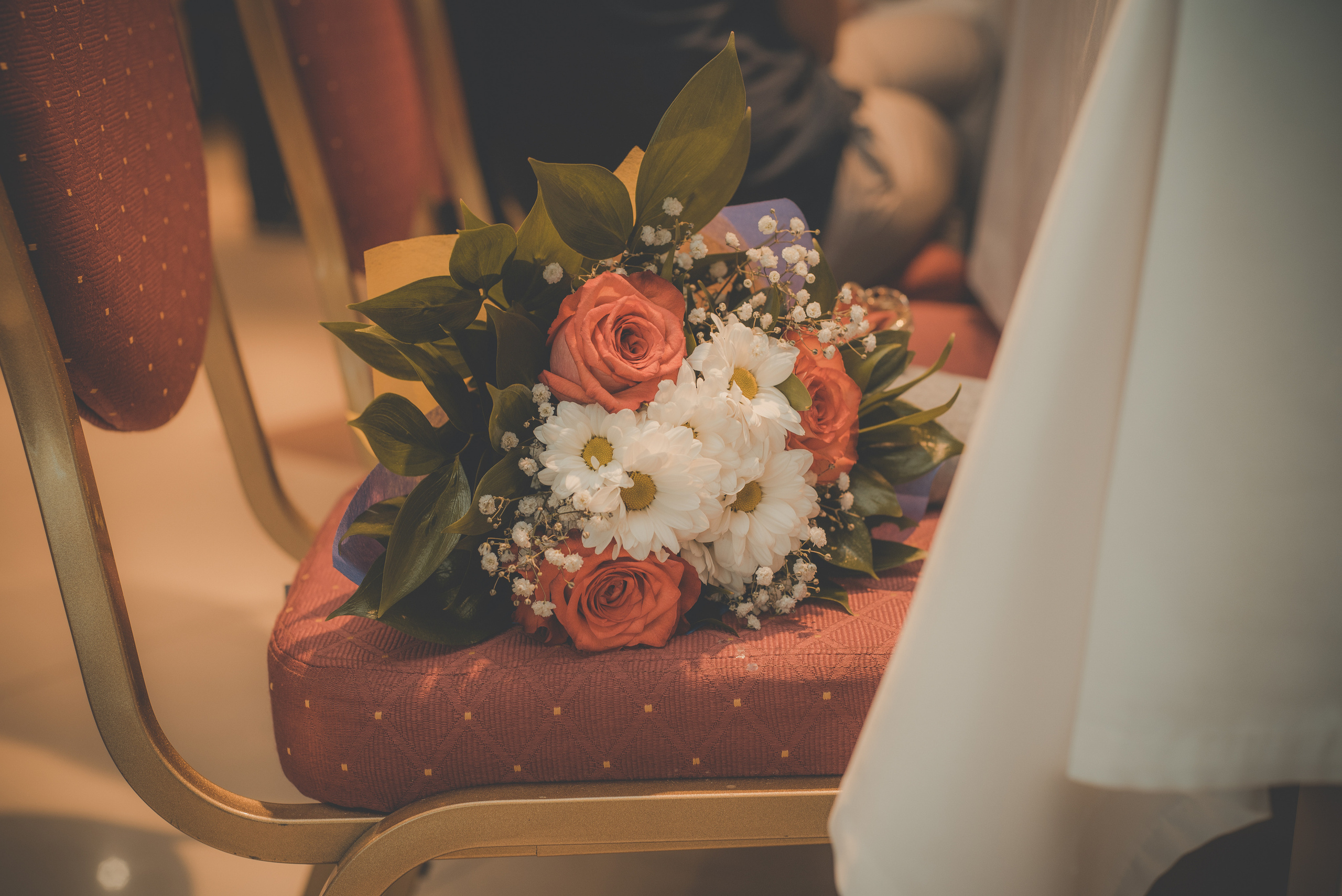 Букет из ромашек и красных роз лежит на стуле в ресторане