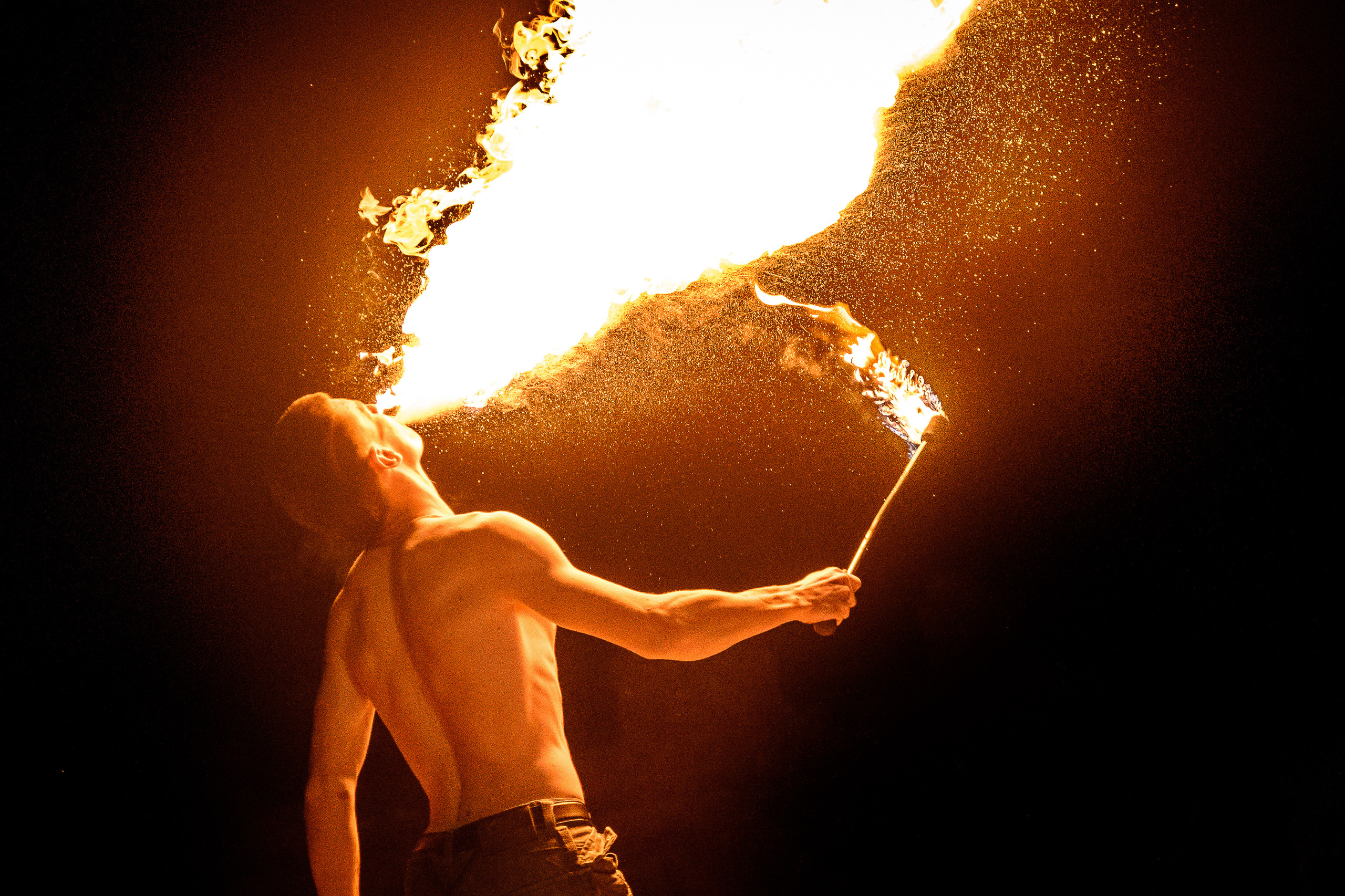 Мужчина делает факел огня изо рта на фаер-шоу