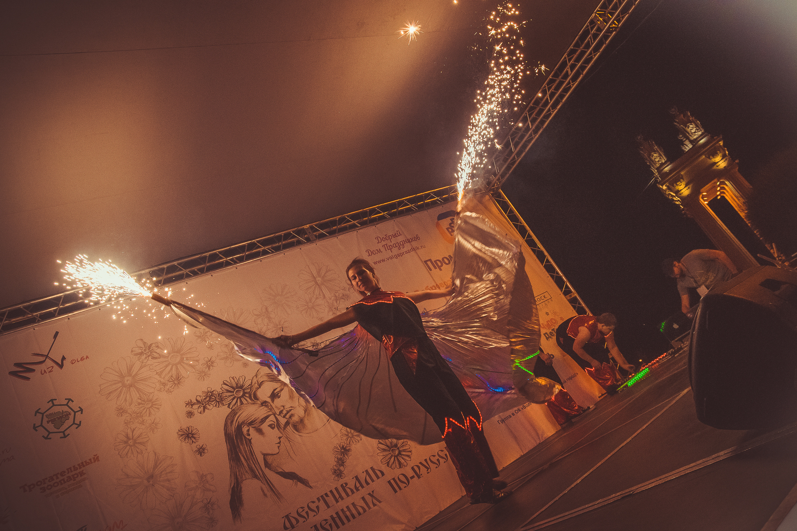 Артист фаер-шоу на сцене с искрящимися факелами