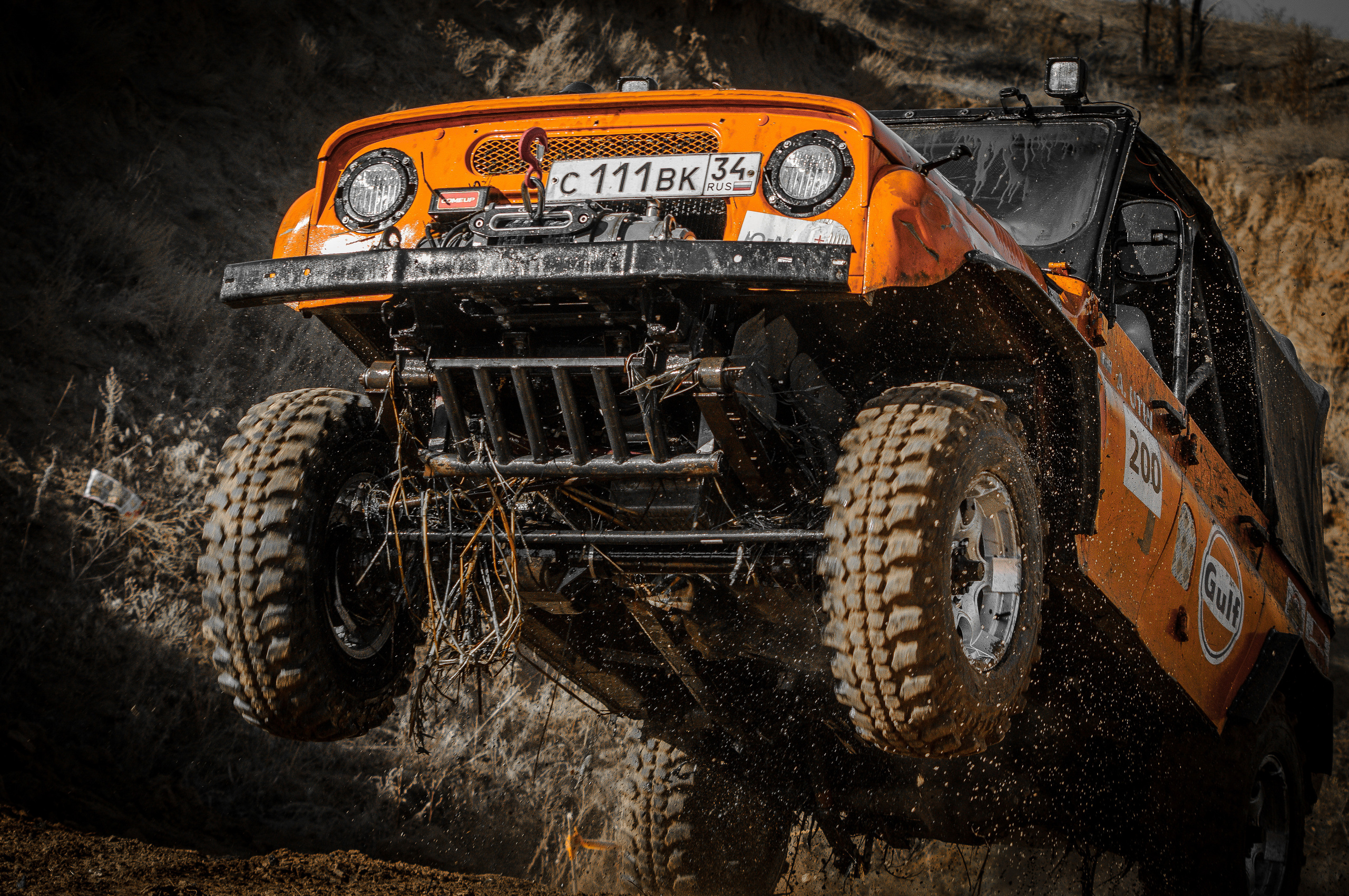 Оранжевый УАЗ заезжает в гору на двух колесах