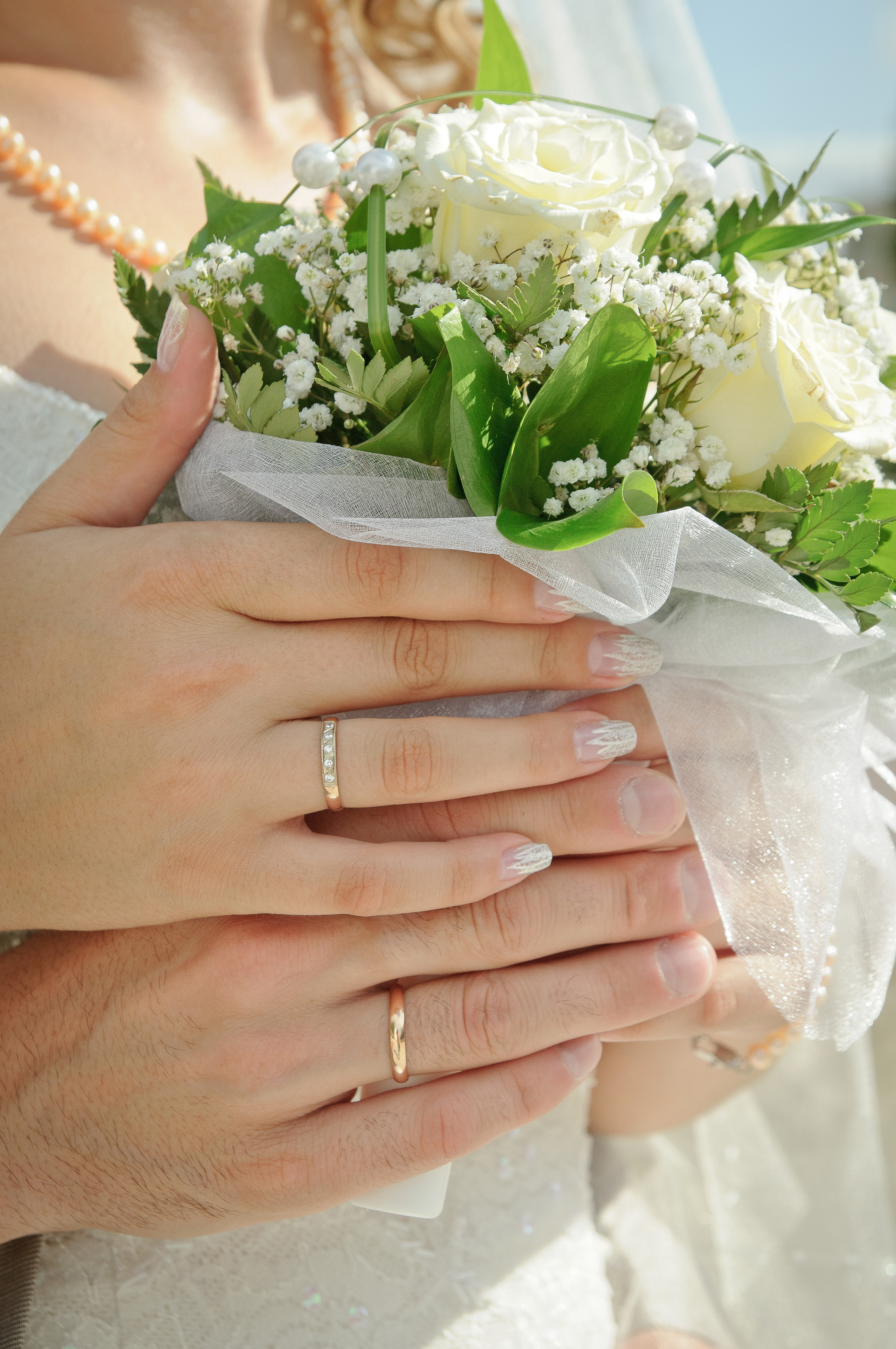 Руки невесты и жениха, держащие букет